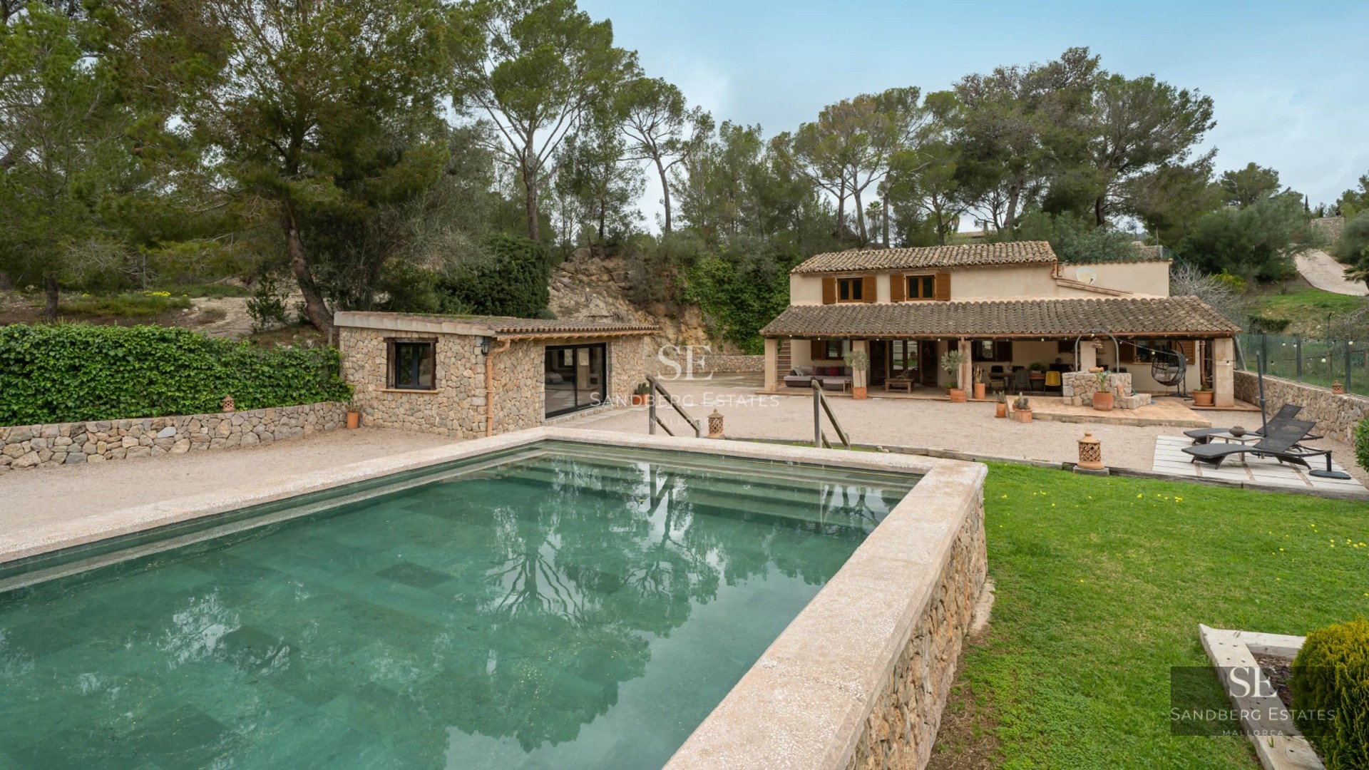 View of modern villa with reflecting pool, designer outdoor furniture, and lush greenery. Minimalist architecture.