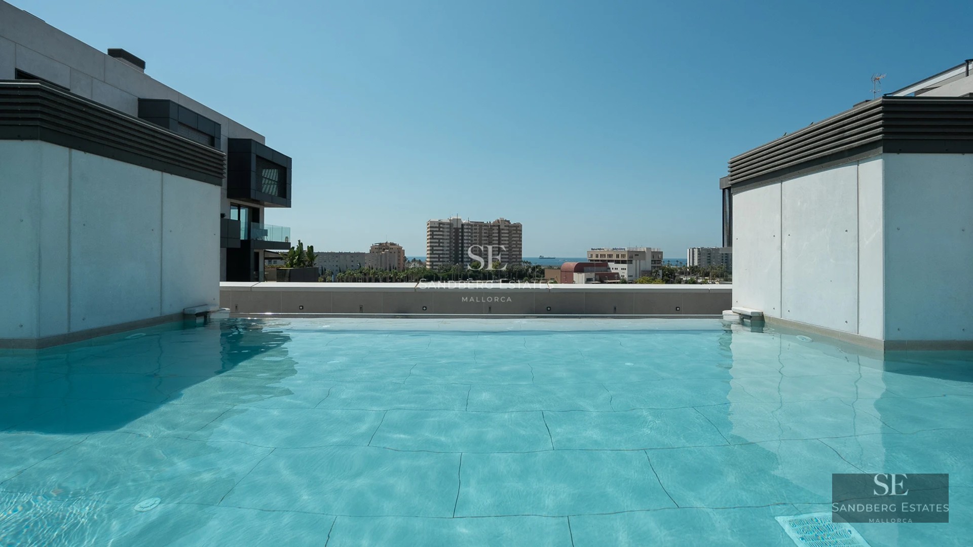 Exterior view of a modern villa featuring an infinity pool, minimalist design, and large windows. Lush garden and blue skies.