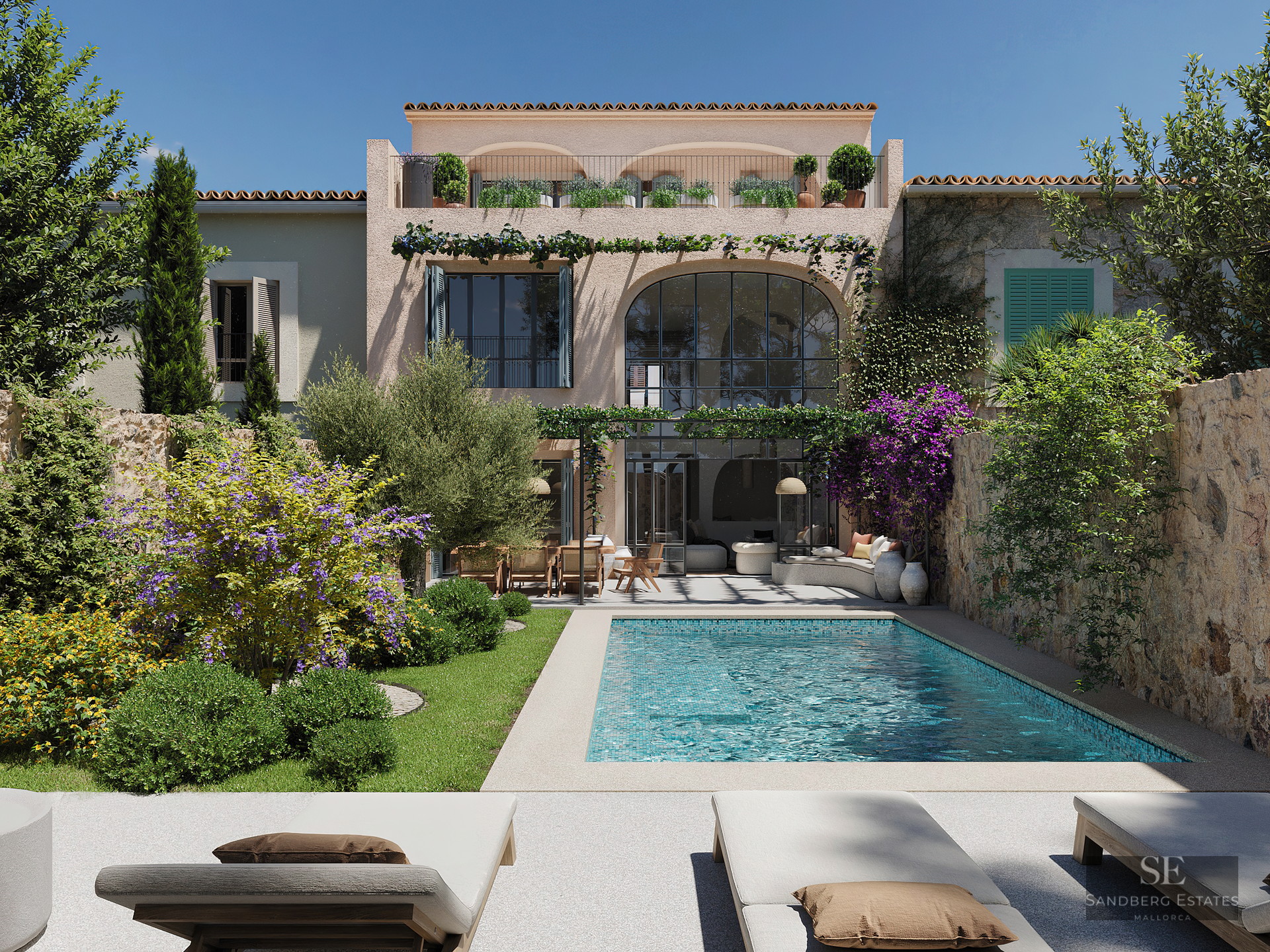 Turquoise swimming pool surrounded by a lush garden and Mediterranean villa facade under a clear blue sky.