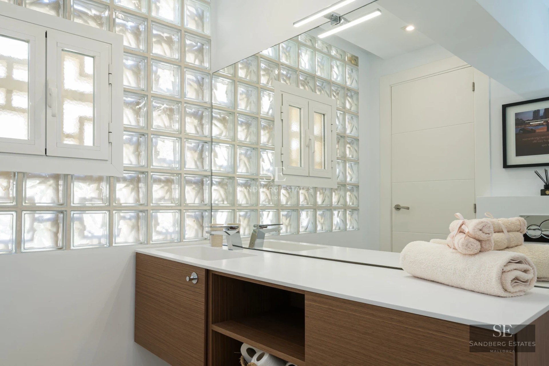 Spacious living room featuring floor-to-ceiling windows offering panoramic sea views, light wood floors, and modern neutral-toned furniture.
