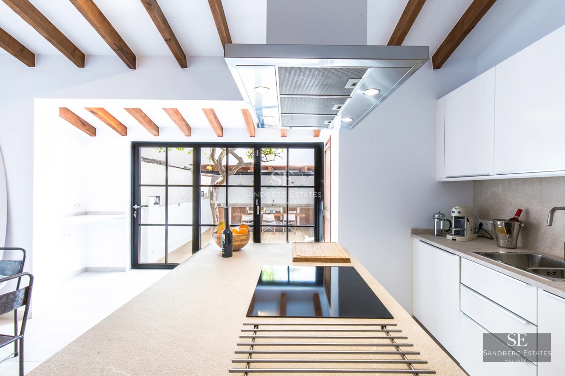 Spacious living room with natural light, large windows, a fireplace, and modern furnishings. Light wood floors and a neutral color palette.