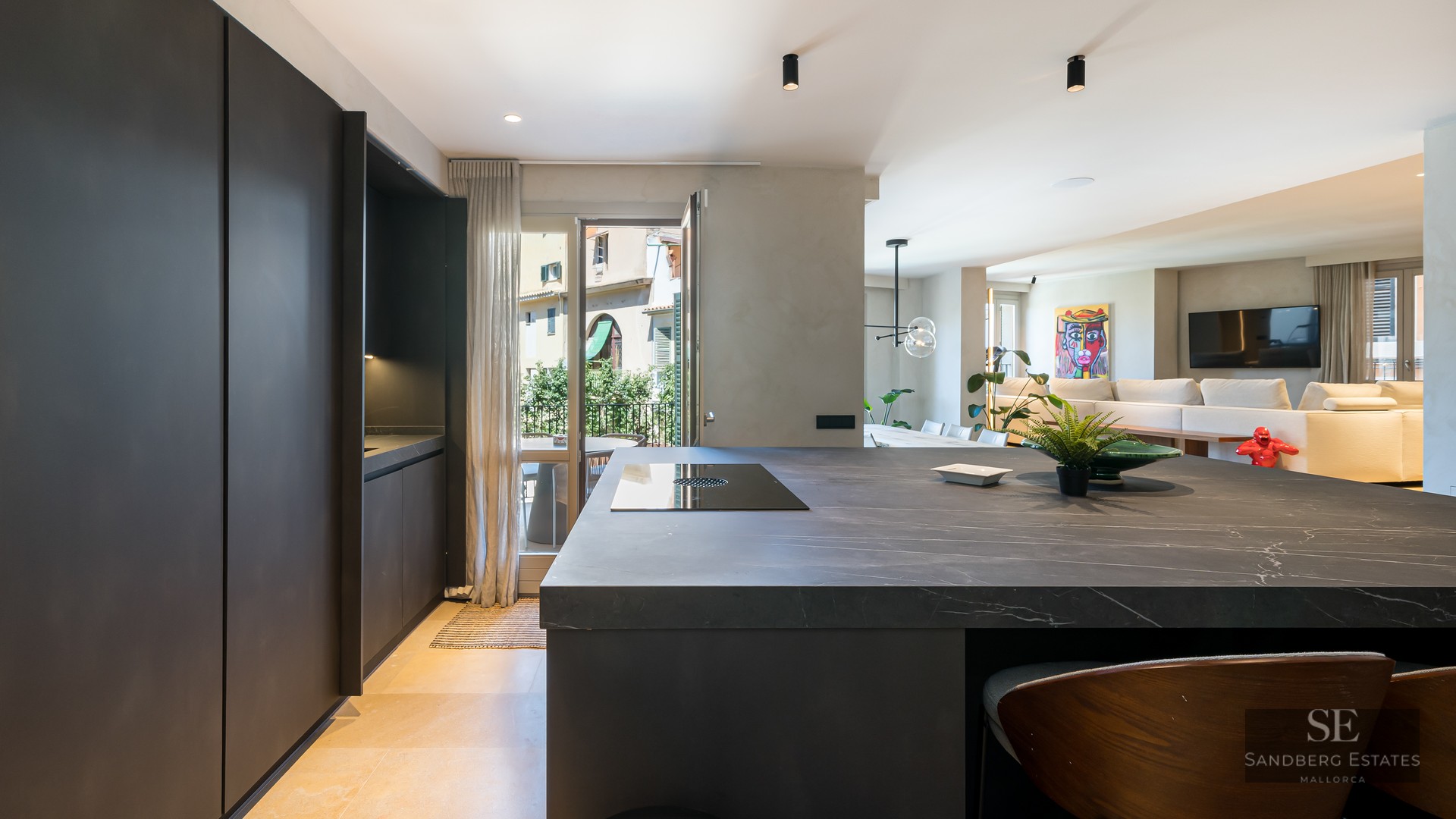 Modern dark stone kitchen island in an open-concept apartment with living area in the background.