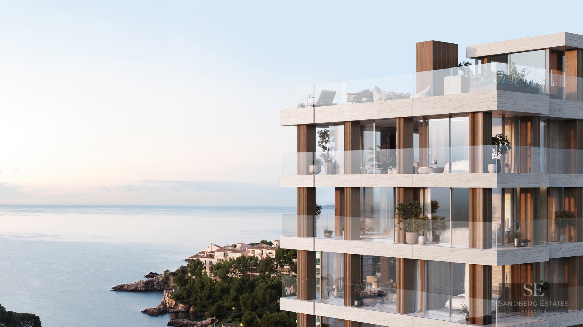 Modern multi-story building with stone facade, glass balconies, and panoramic sea views at sunset.