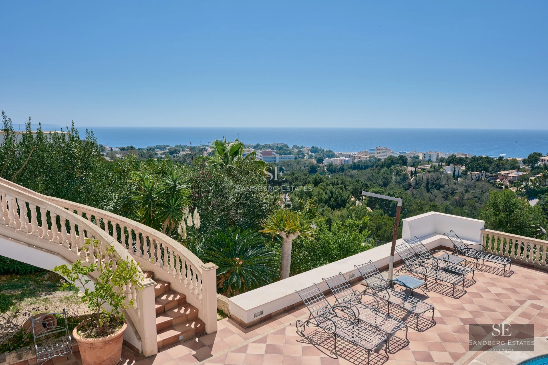 Spacious balcony overlooking the sea. Modern design, wooden floor, glass railing, and minimalist outdoor furniture.