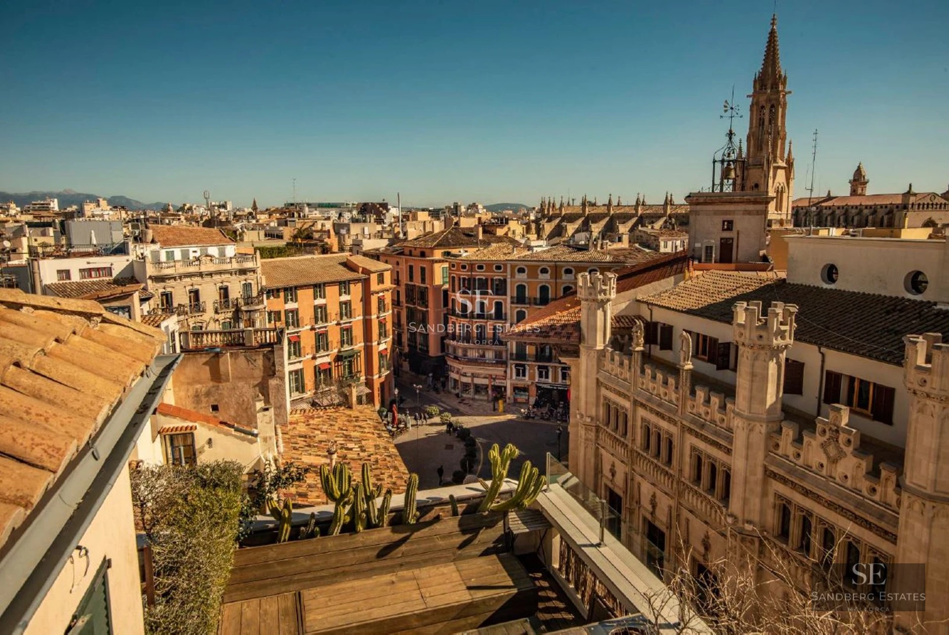 Spacious balcony with sea view, furnished with wicker and wood furniture. Awning for shade and modern glass railing.