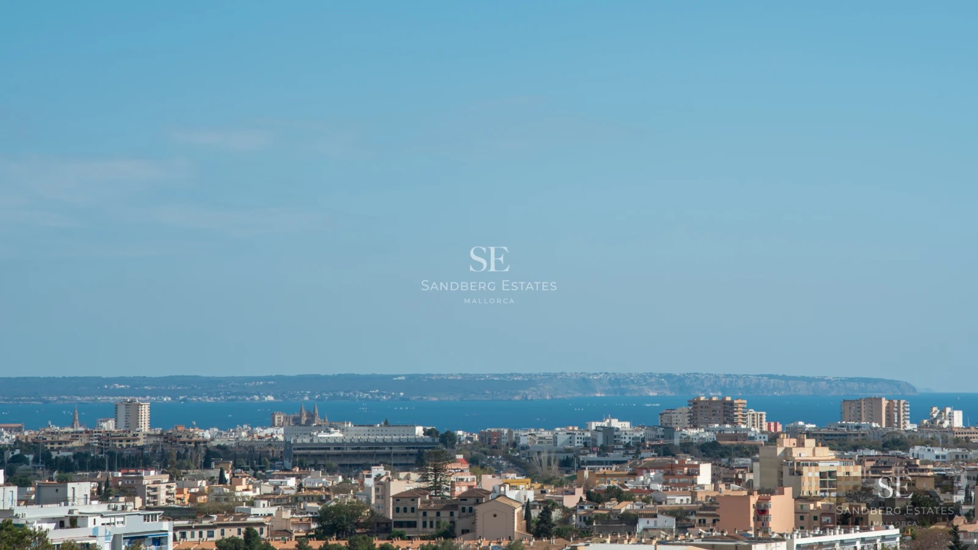 Spacious living room with floor-to-ceiling windows, light wood flooring, fireplace, and sea view. Modern design with minimalist furniture.