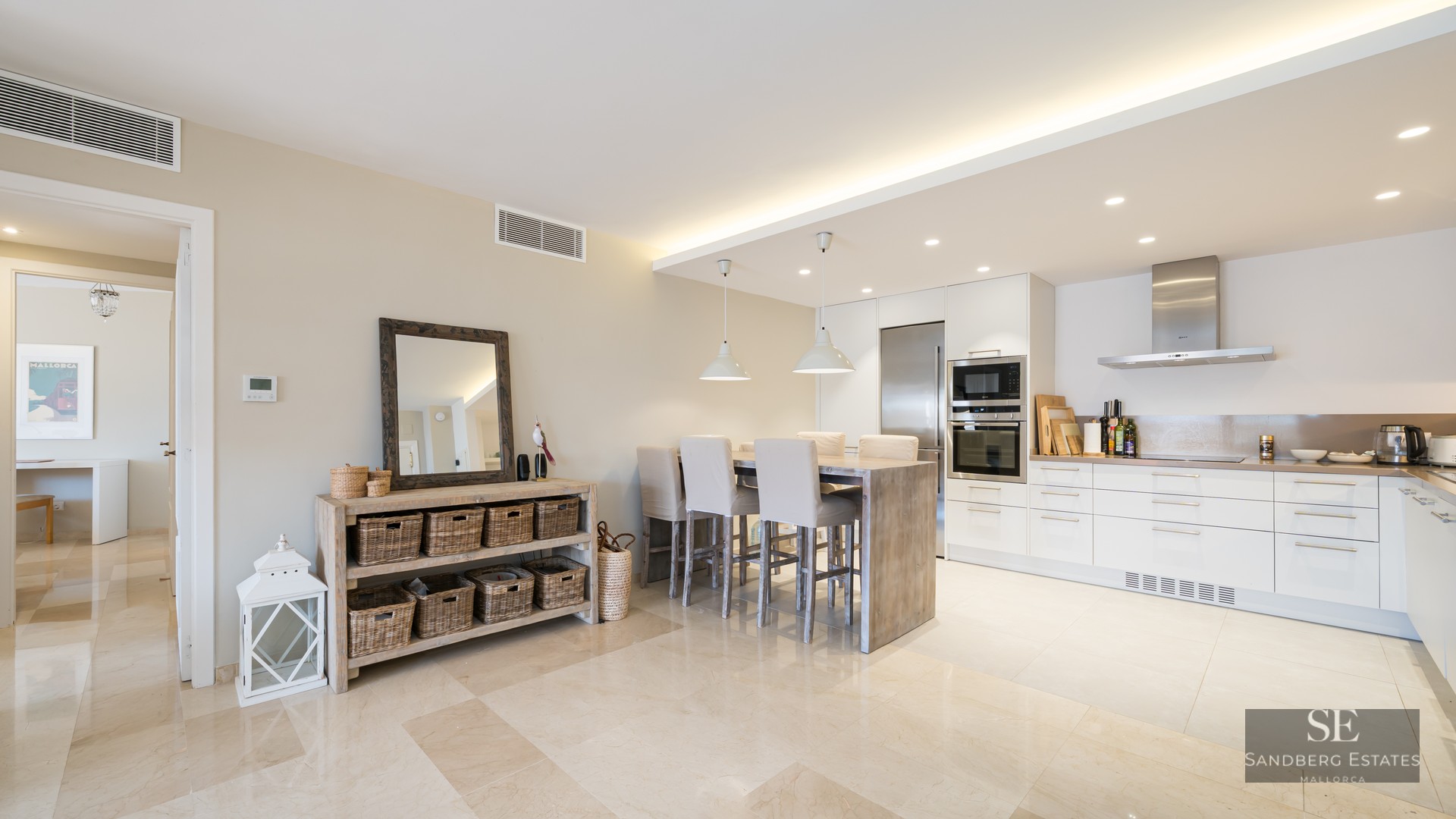 Bright modern kitchen with white cabinets, stainless steel appliances, and a wooden dining island with high chairs.