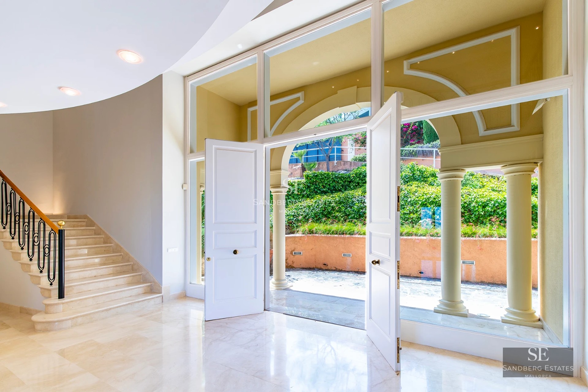 Exterior of a modern villa with infinity pool, lush garden, and spacious terraces offering panoramic sea views.