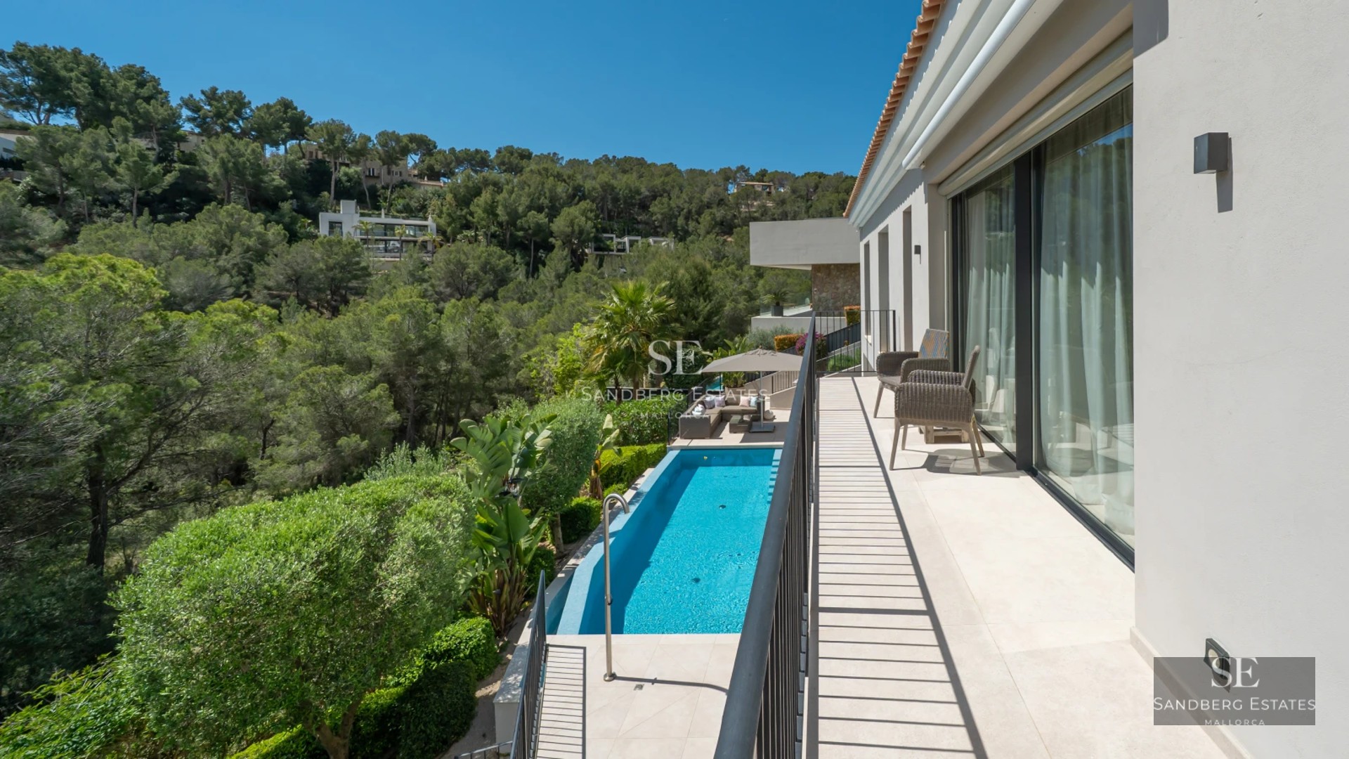 Exterior view of a modern villa featuring an infinity pool, expansive terraces, and lush garden. Minimalist architectural design and luxury finishes.