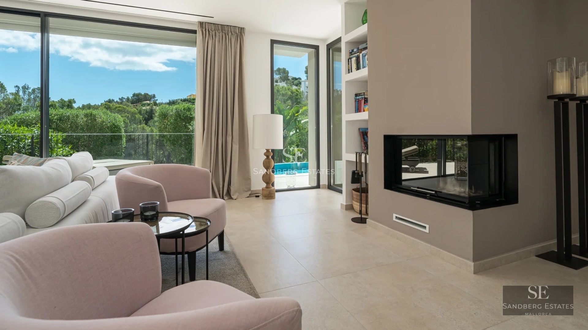 Bright living room with large windows overlooking the sea. Modern interior with beige sofa, coffee table, and stylish decorative details.