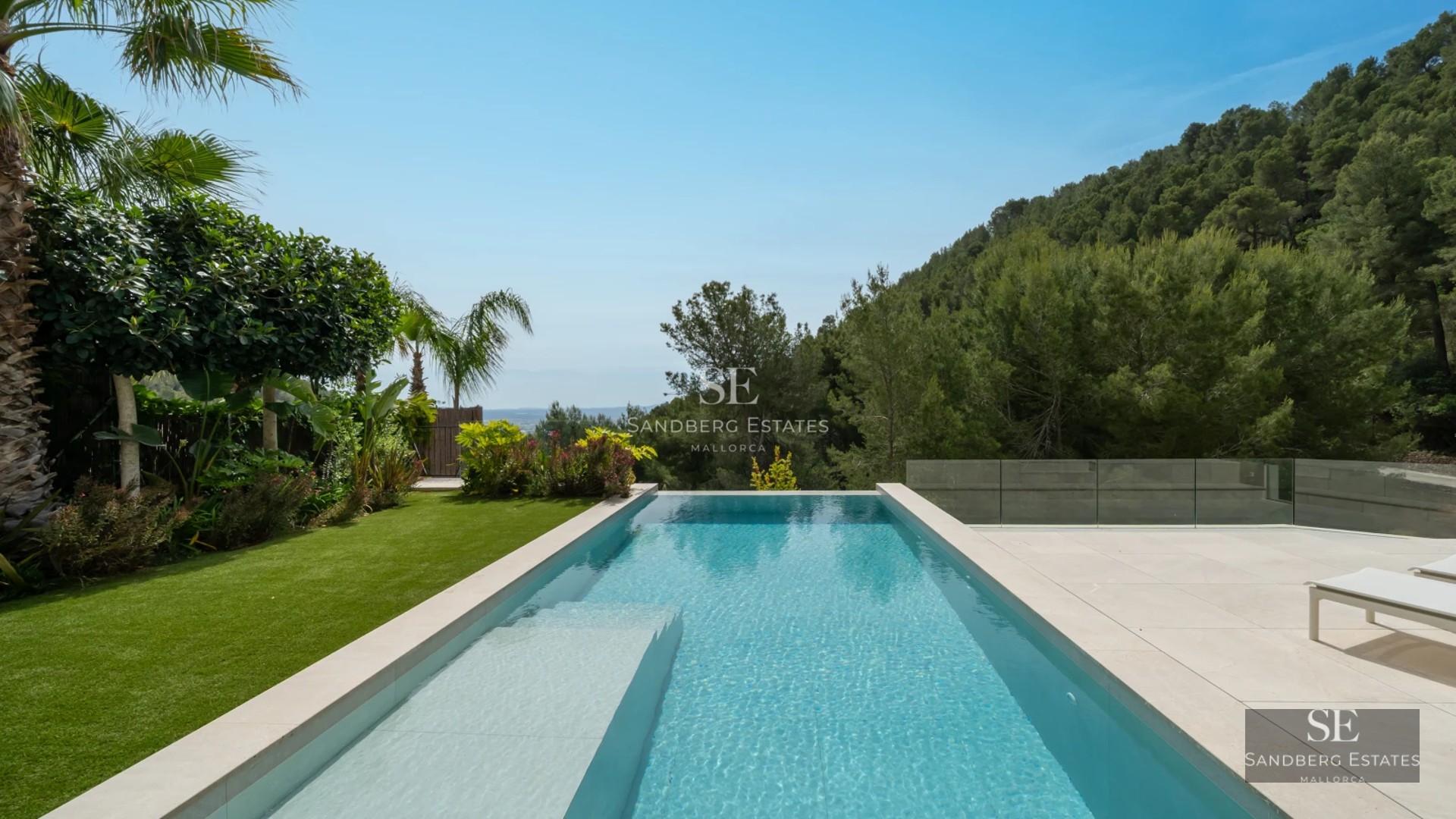 Exterior view of a modern villa featuring a reflective pool, expansive windows, and minimalist design in a landscaped setting.