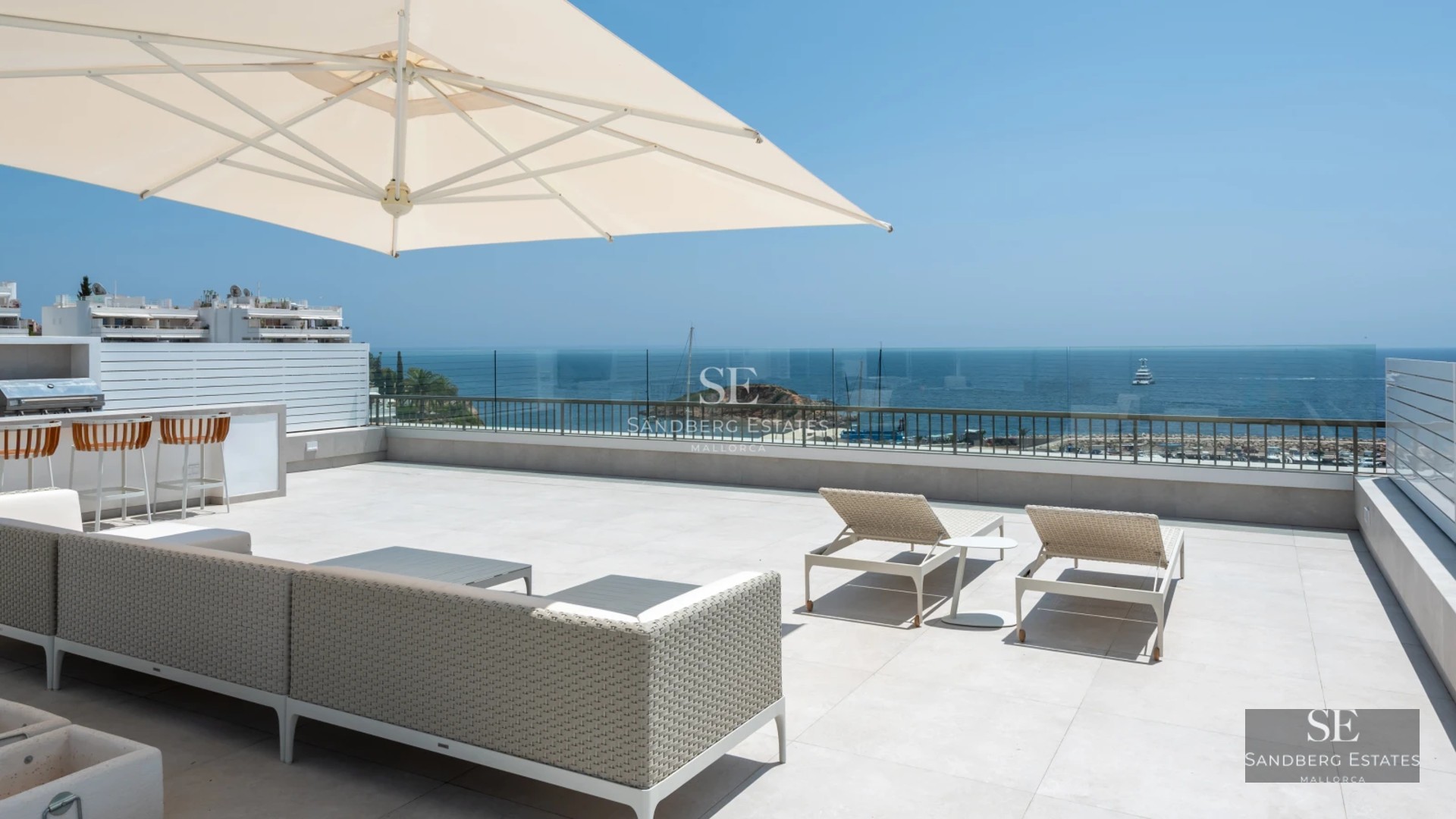 Spacious balcony with panoramic sea view. Modern design, glass railing, soft ambient lighting, and stylish outdoor furniture.