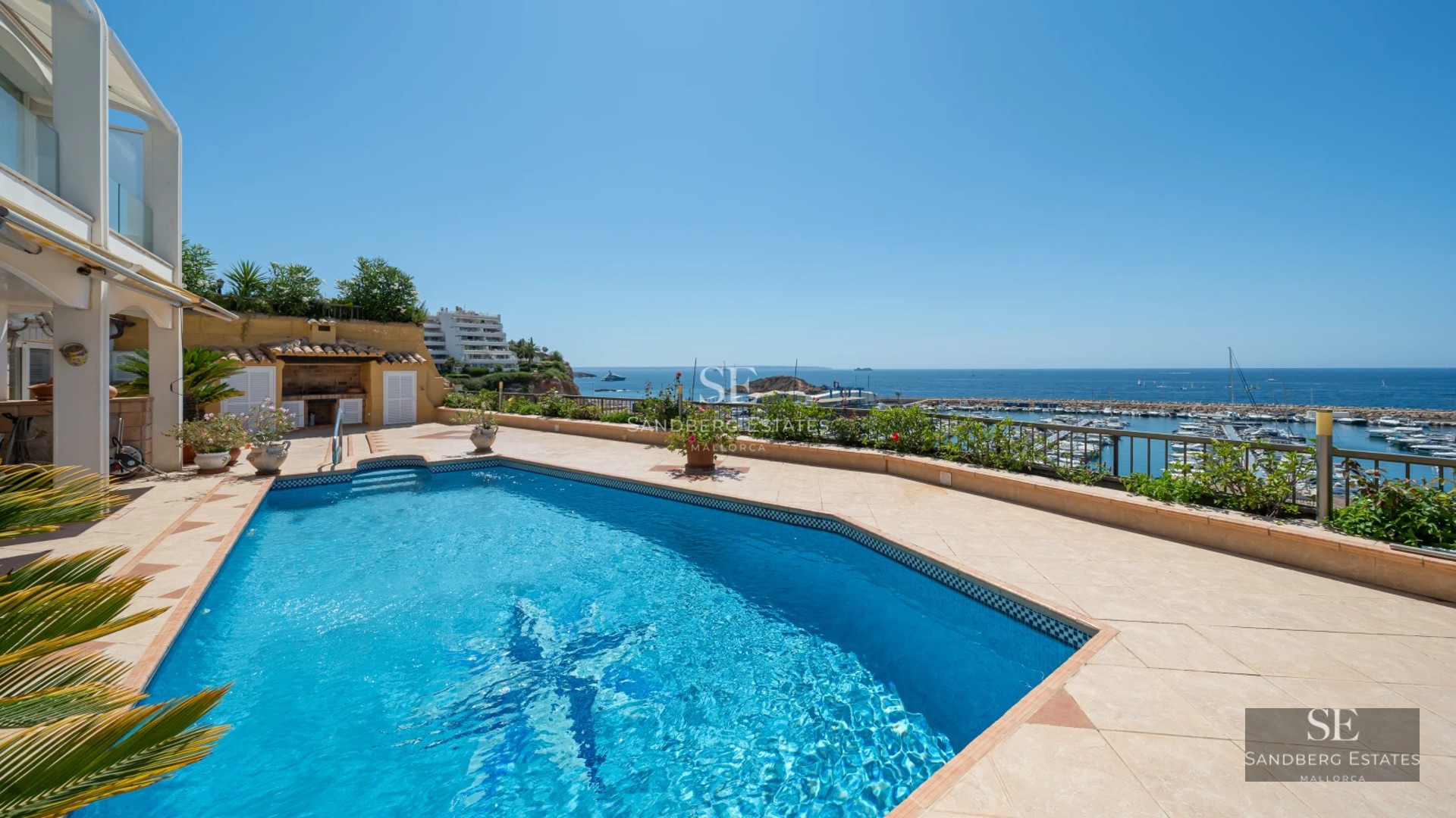 View of the pool and terrace of a modern villa with large windows and lush greenery. Elegant design and luxury finishes.