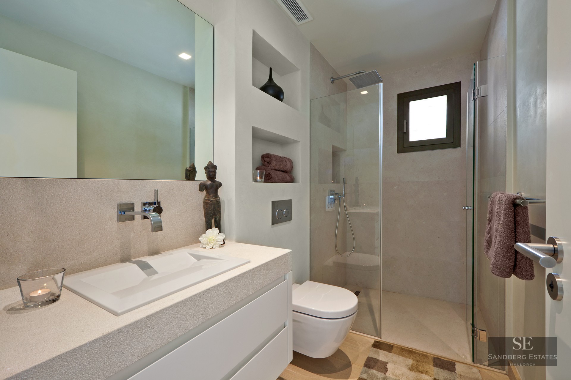 Modern bathroom featuring a stone vanity, wall-mounted toilet, and glass walk-in rain shower.