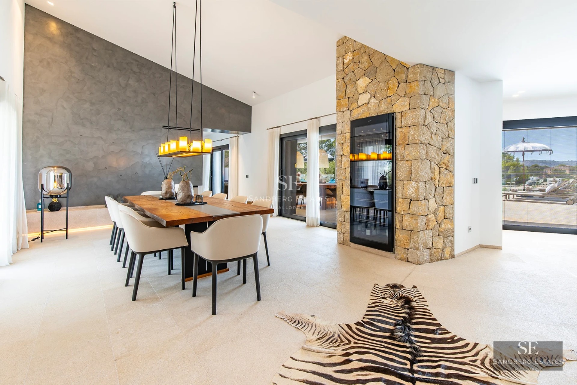 Exterior view of a modern villa with an infinity pool, large windows, and minimalist design. Manicured lawn and clear sky.