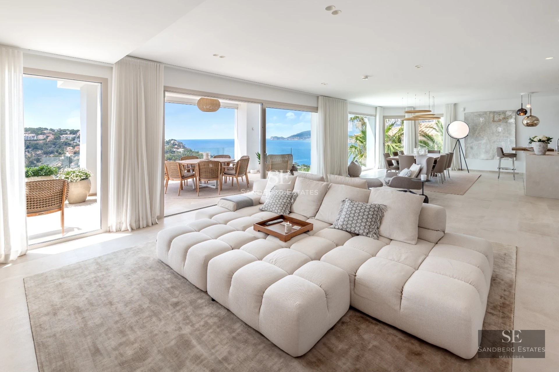 Modern balcony with glass railing, light wood flooring, sea view, and minimalist designer furniture. Spacious and bright space.