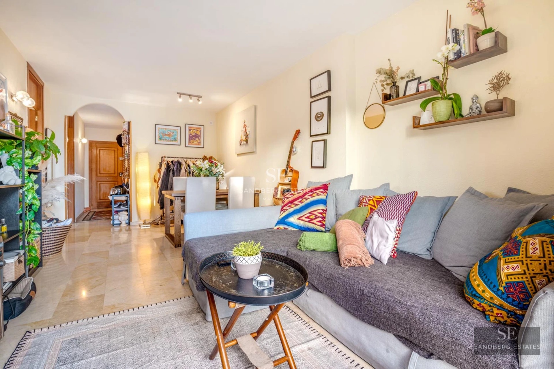 Salon lumineux avec grandes baies vitrées donnant sur piscine. Canapé modulable beige, tapis texturé et décoration minimaliste. Design moderne et élégant.