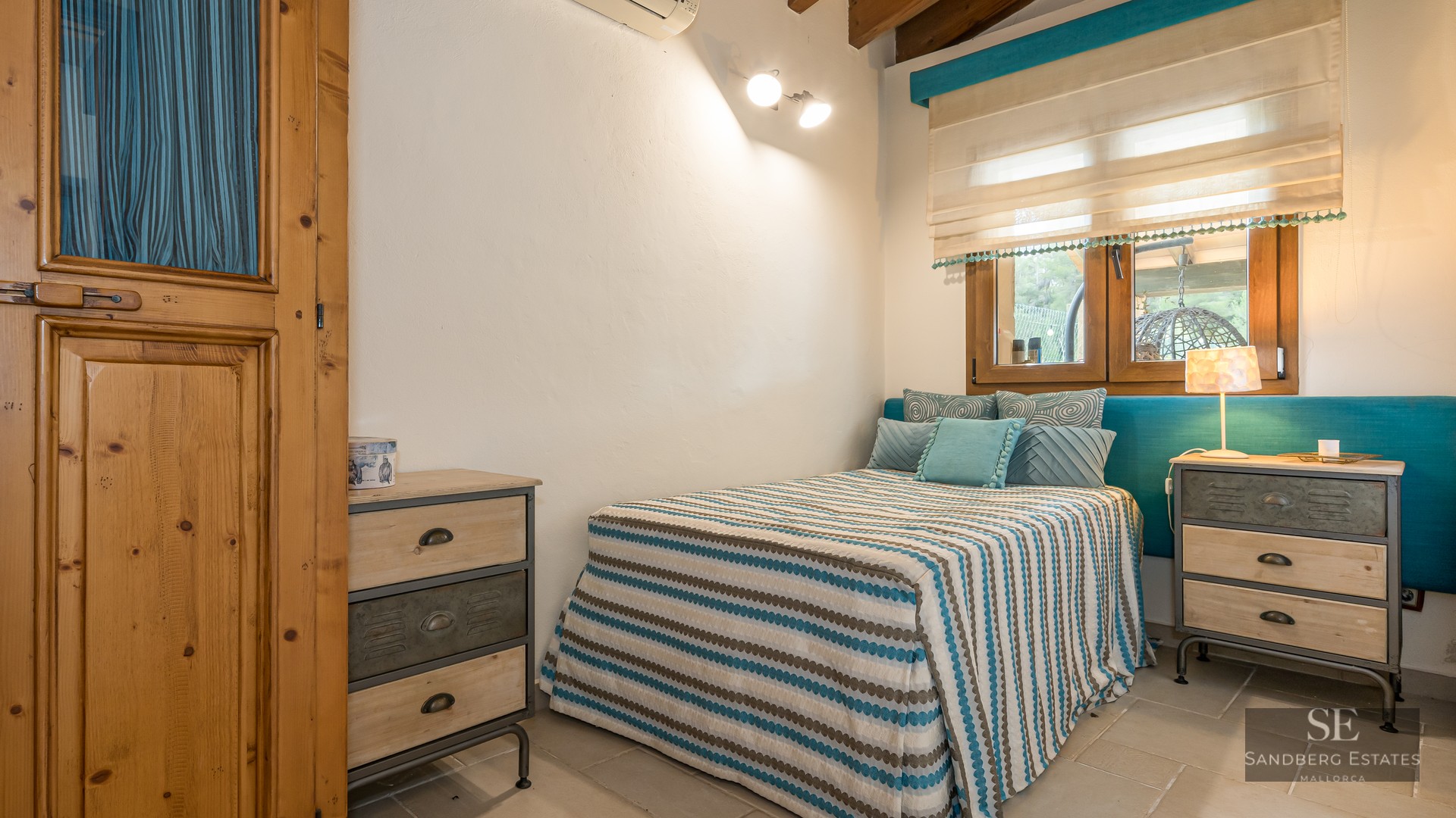 Bedroom featuring a striped bed, teal headboard, wooden furniture, and industrial-style nightstands.
