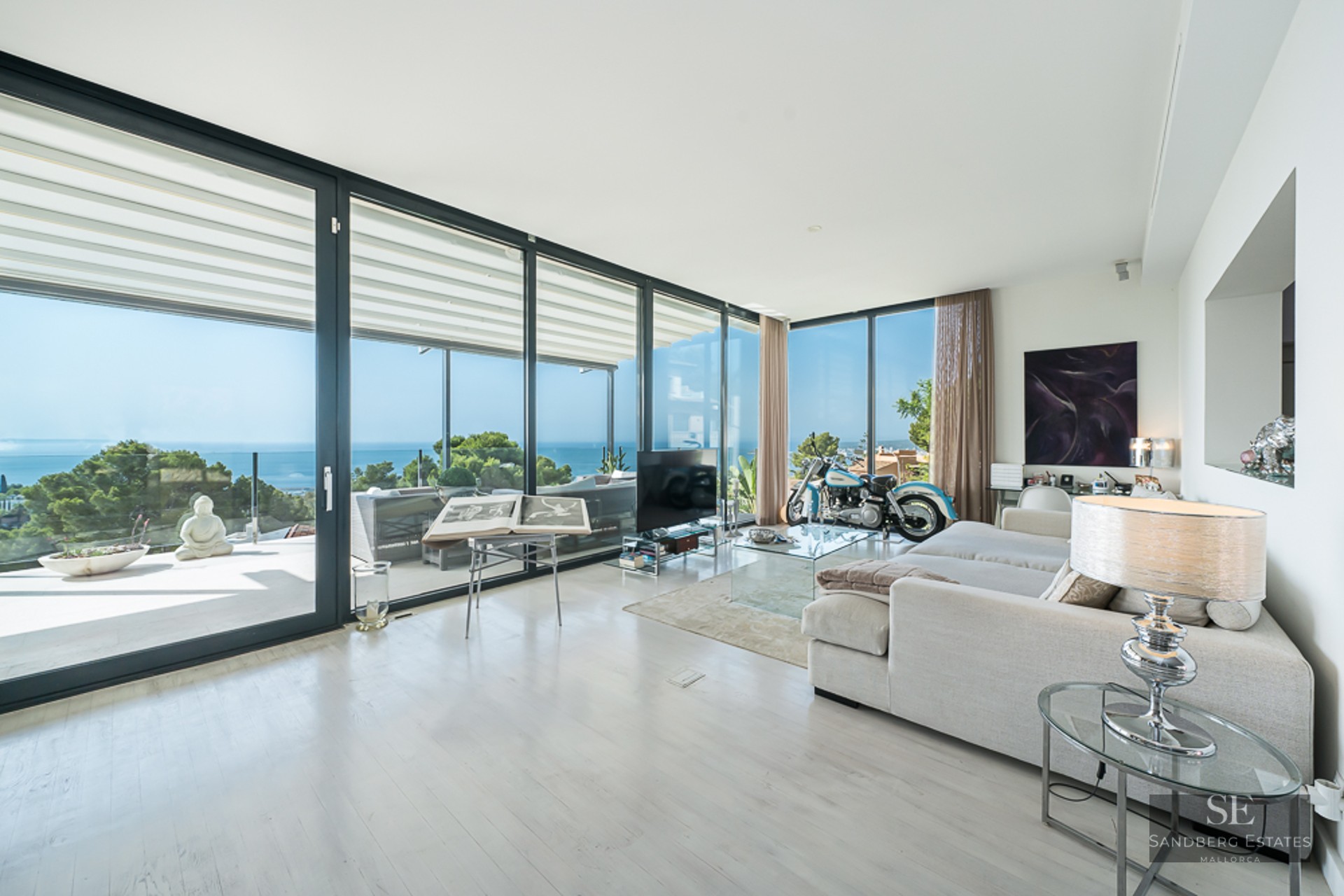 Bright, spacious living room with floor-to-ceiling glass doors, a large white sofa, and a breathtaking view of the ocean.