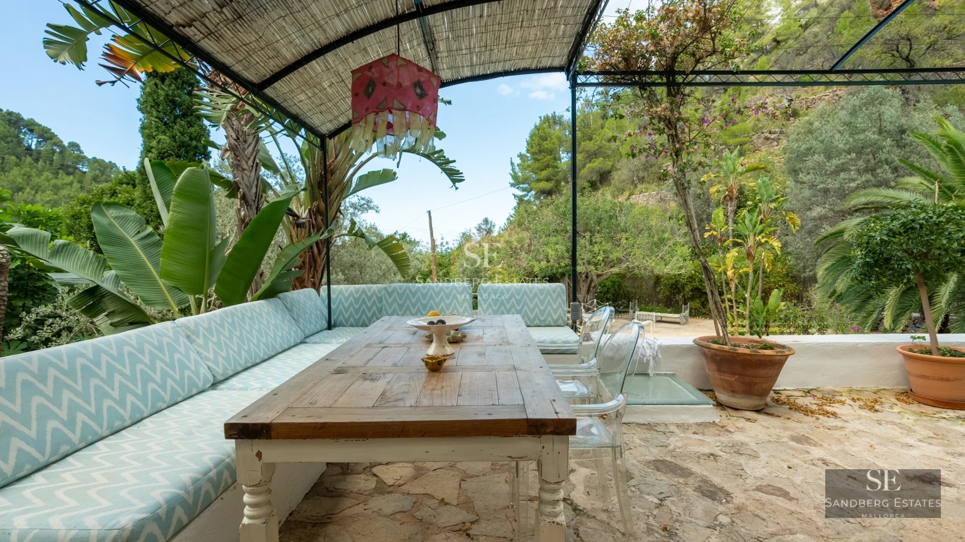 Exterior view of a luxurious modern villa with a pool, manicured garden, and large windows reflecting sunlight.