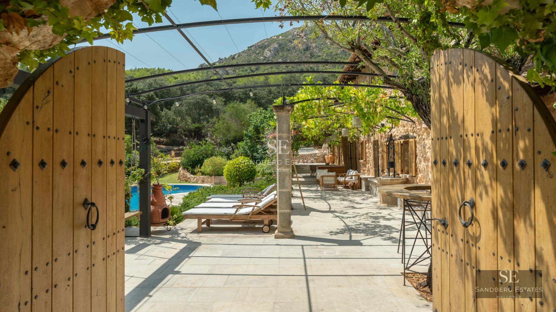 View of pool surrounded by lush greenery, featuring a wooden deck and minimalist modern architecture in the background.
