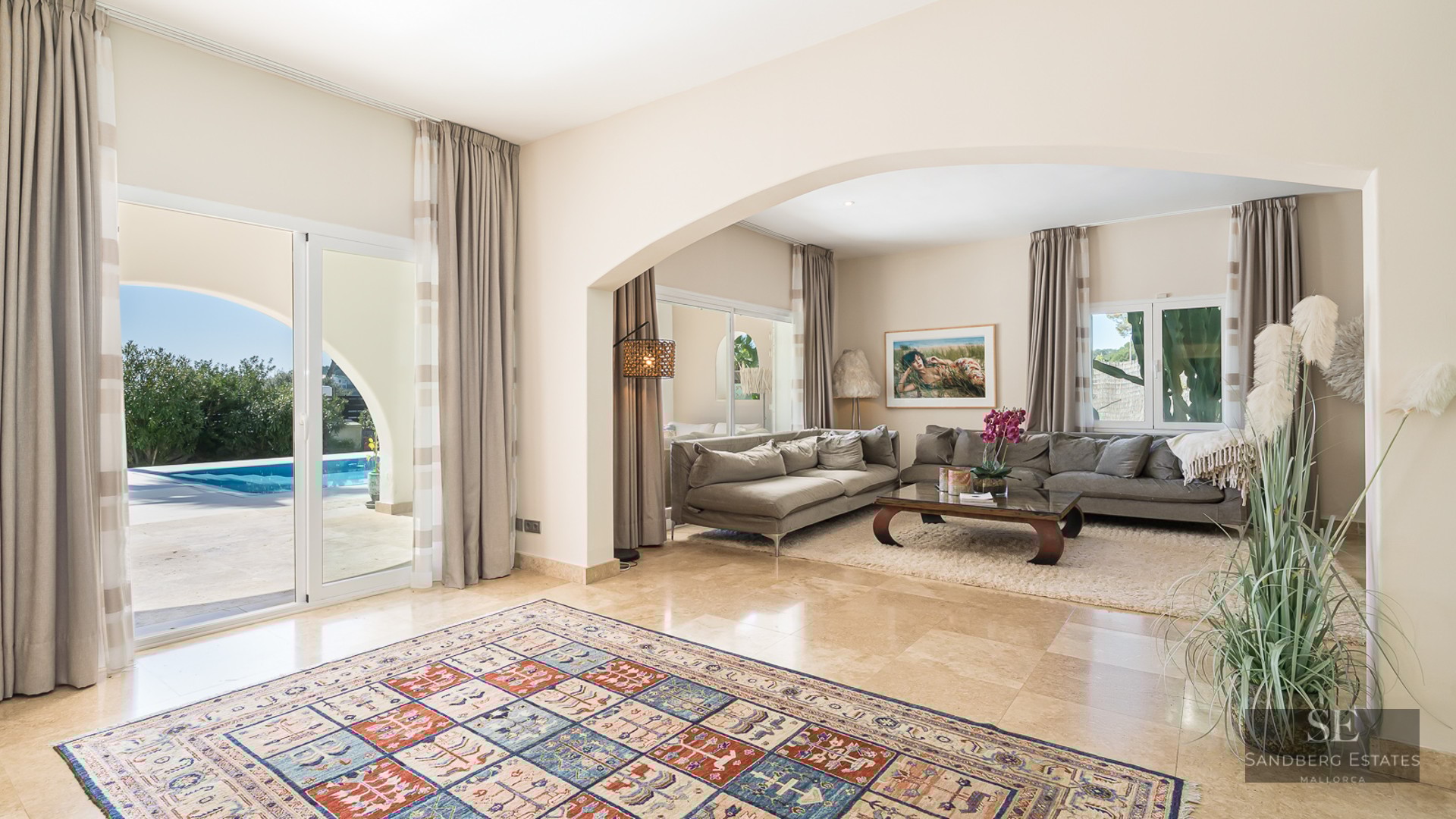 Spacious modern living room with marble floors, gray sofas, and sliding glass doors opening to a blue swimming pool.