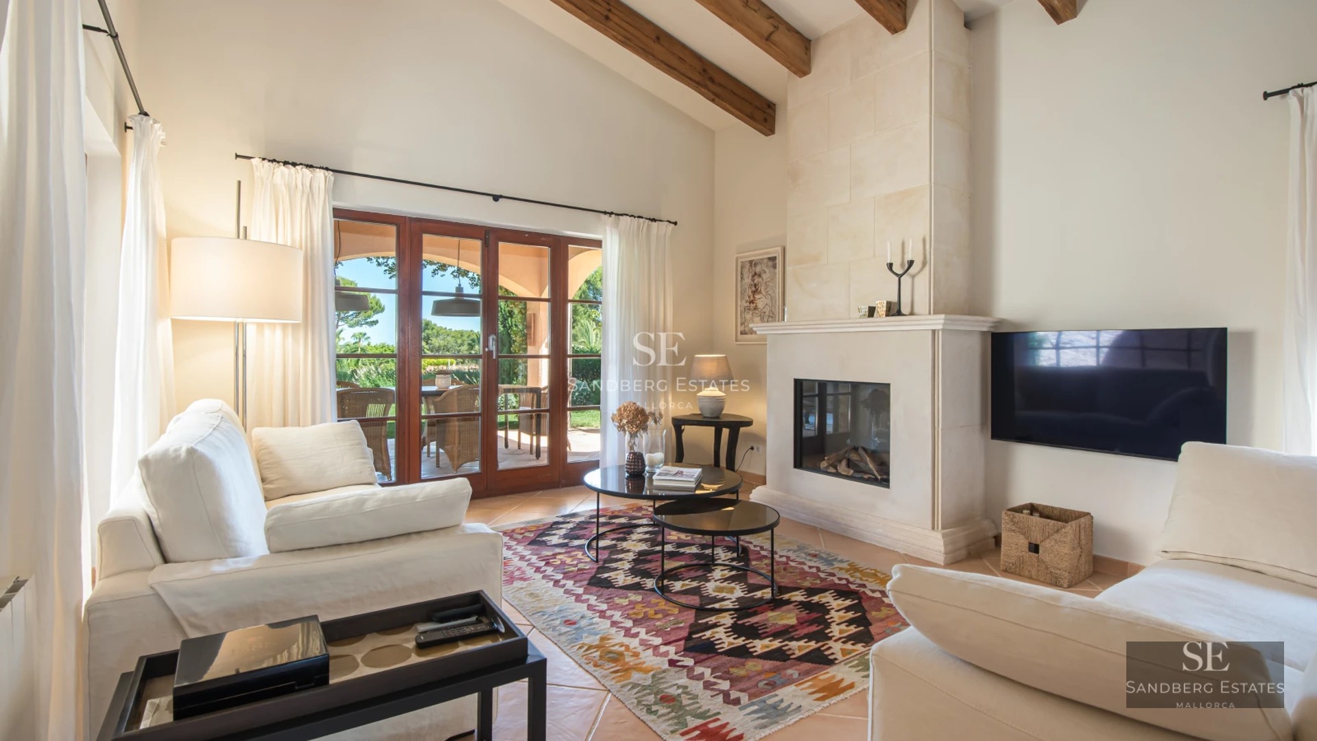 Spacious bright living room with designer sofas, modern fireplace, and panoramic windows overlooking the garden and pool.