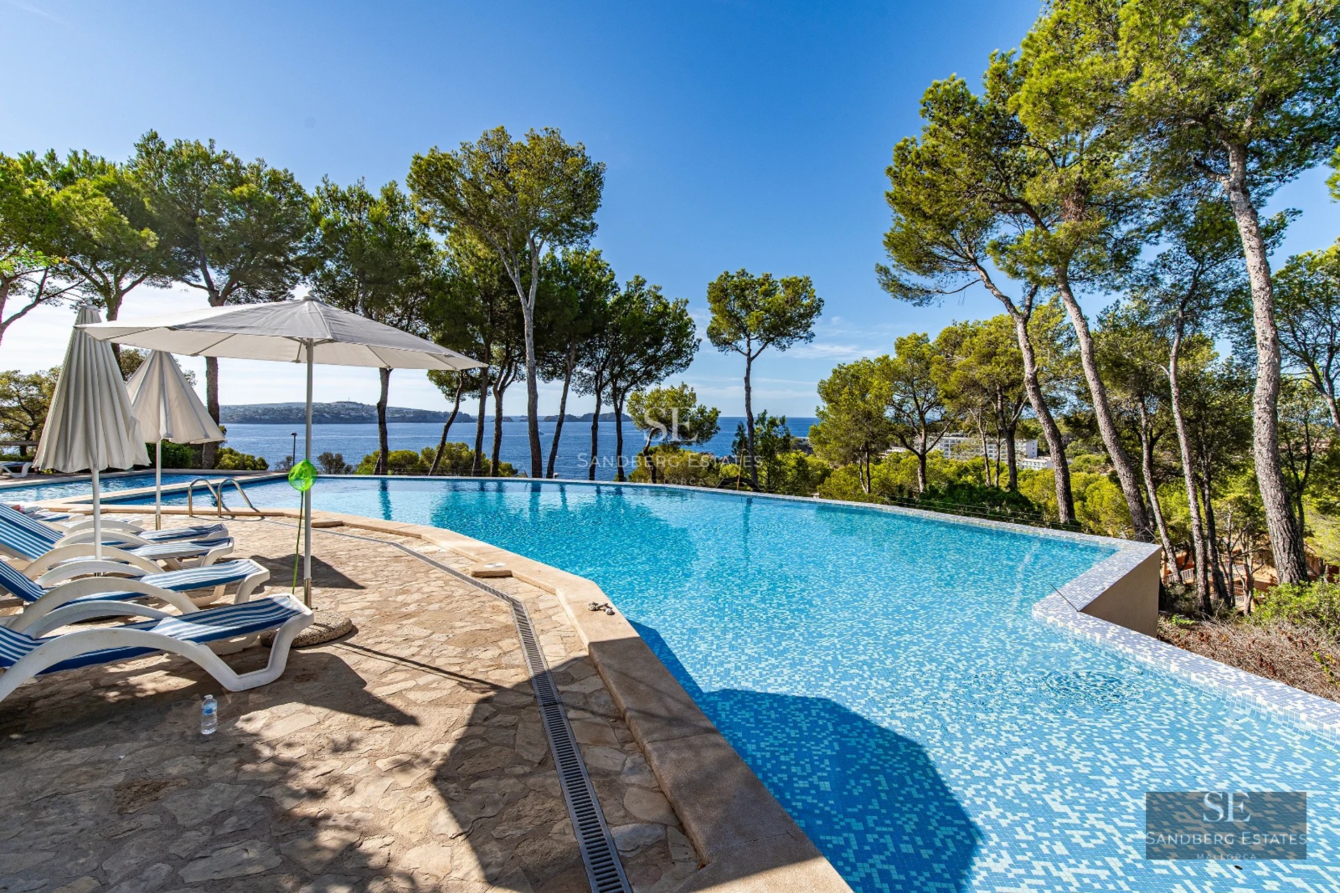 Exterior view of a modern villa featuring an infinity pool and spacious terraces. Minimalist architecture and panoramic sea views.