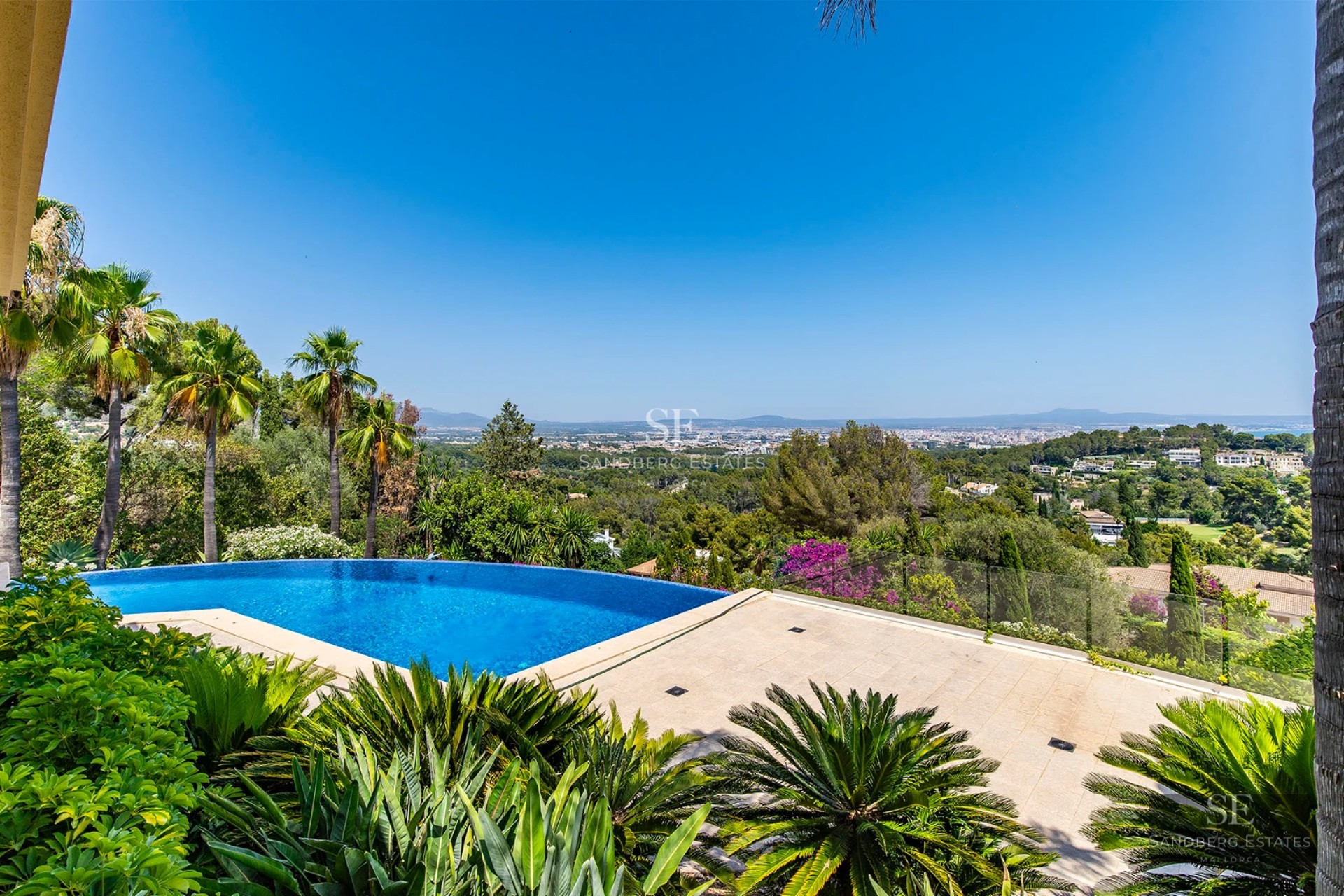 Wide view of modern villa featuring an infinity pool, sea views, minimalist design, large terraces and elegant outdoor furniture.