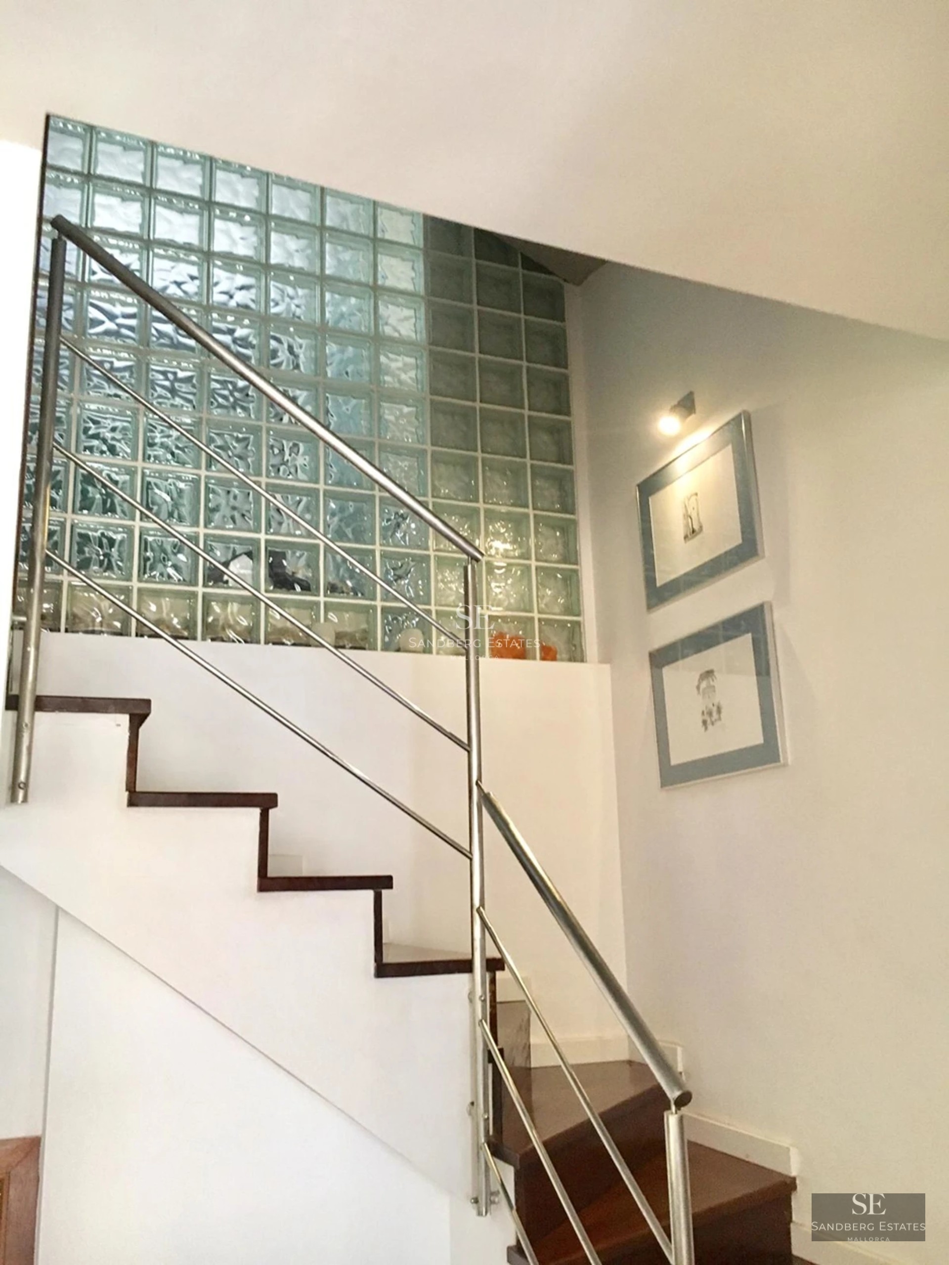 Wide view of a swimming pool with lounge chairs and umbrellas. Modern and minimalist architecture. Green lawn and blue sky.