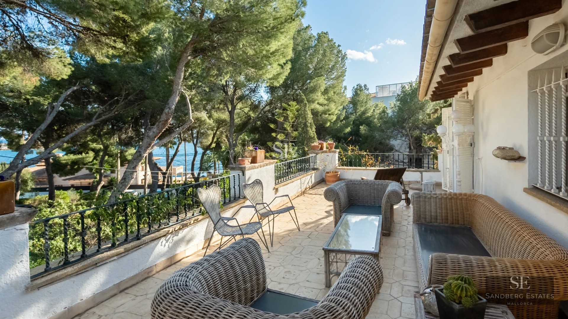 Large swimming pool surrounded by lush greenery. Modern architecture with large windows and spacious terrace. Warm and inviting lighting.