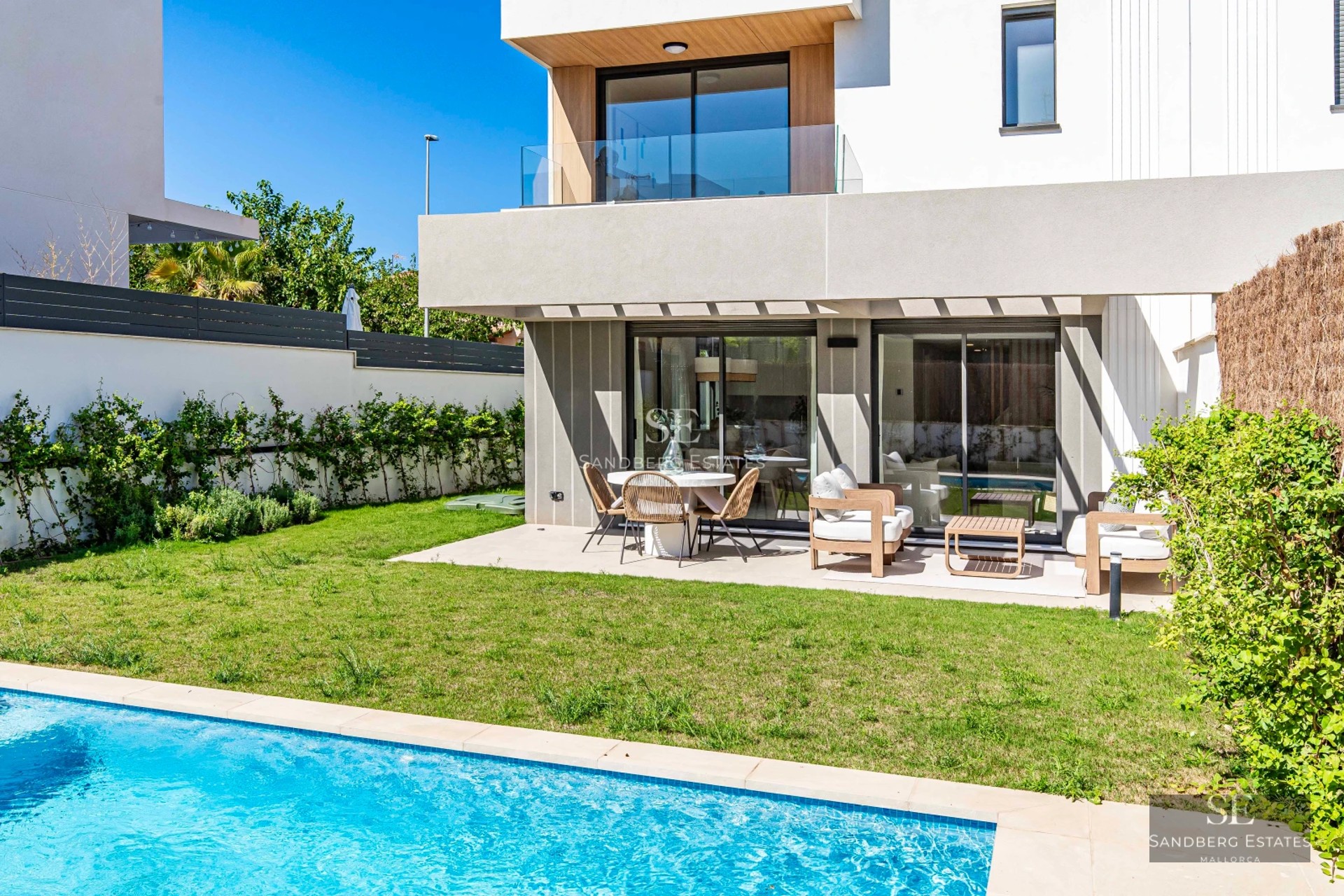 View of a luxurious villa with a pool and lush garden. Modern architecture featuring large windows and high-quality materials.