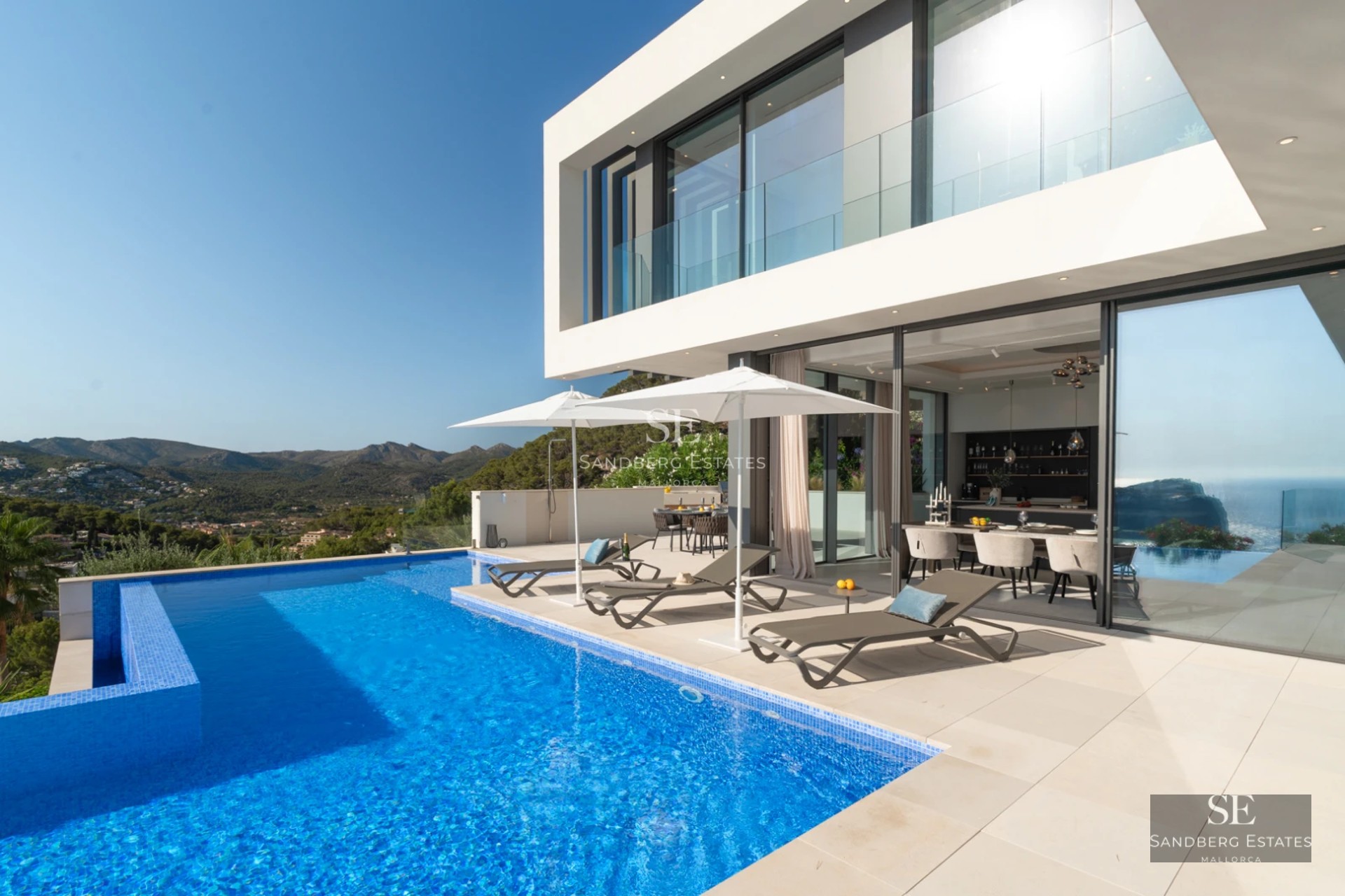 Spacious living room with balcony and sea view. Modern, bright design, featuring large windows and light wood floors.
