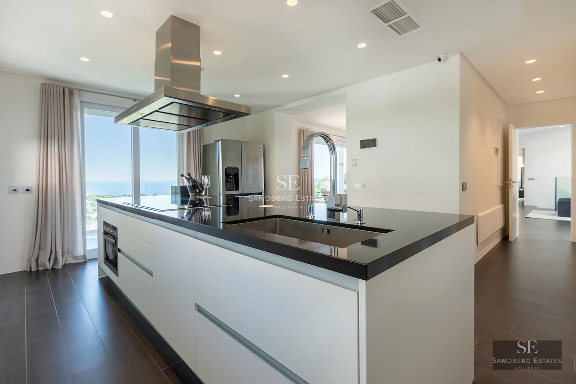Sleek kitchen island with black countertop, stainless steel appliances, and a stunning ocean view through a large window.