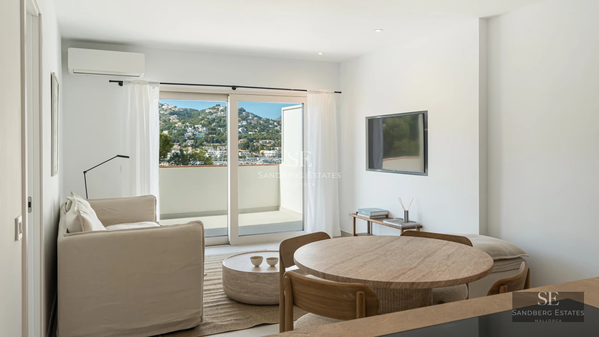 Spacious living room featuring expansive windows, designer sofas, a fireplace, and panoramic sea views. Natural lighting and hardwood floors.