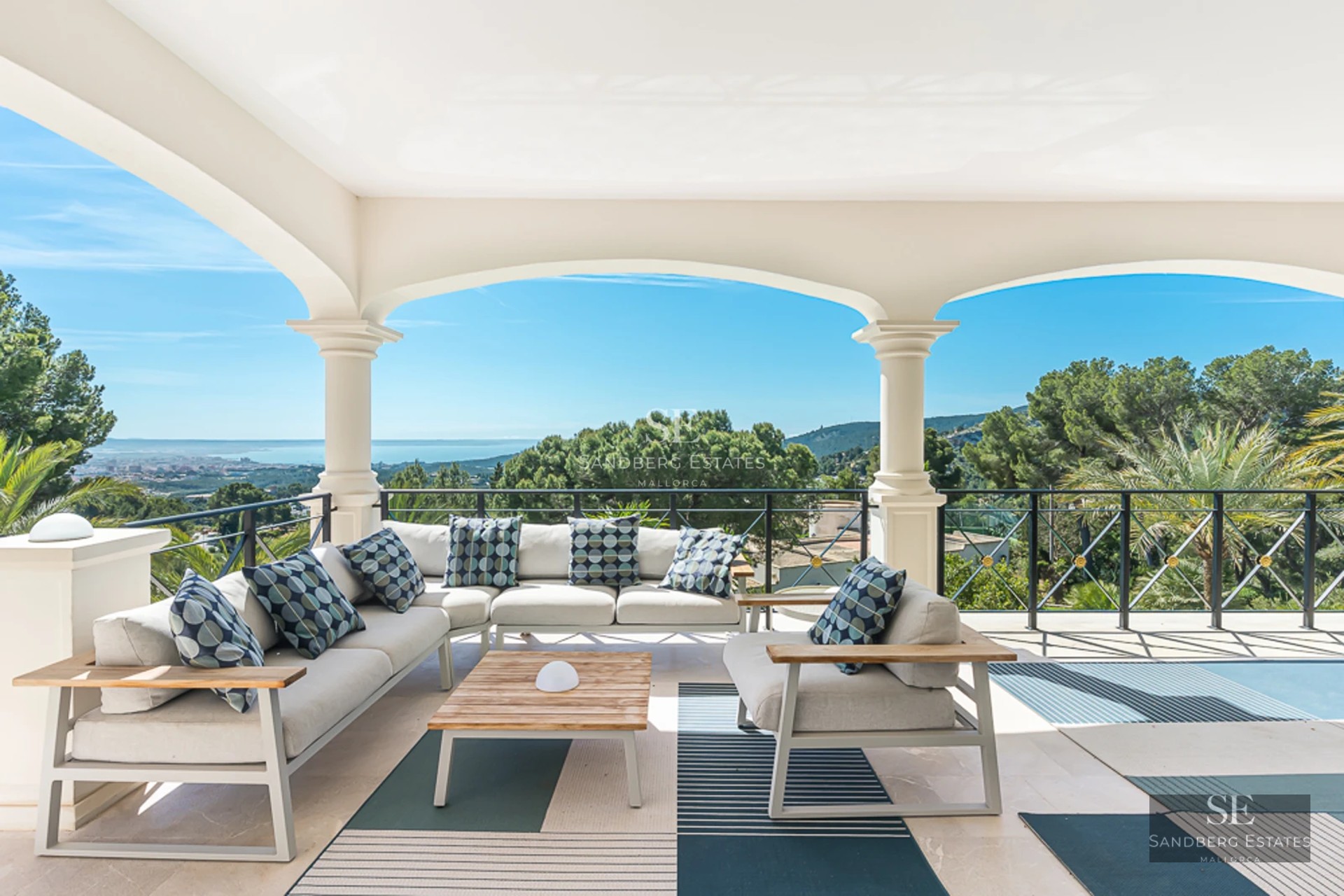 Spacious sea view balcony with modern furniture, glass railing, gray tile flooring, and retractable awning.