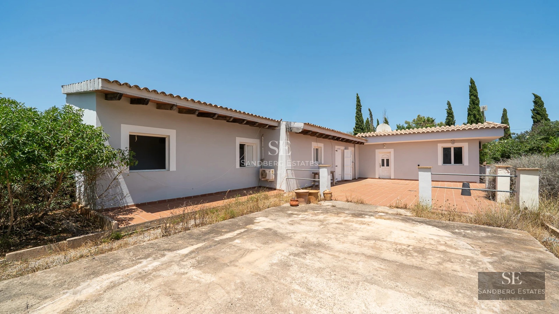 View of a luxurious pool surrounded by a lush garden, with a modern house featuring large windows and minimalist architecture.