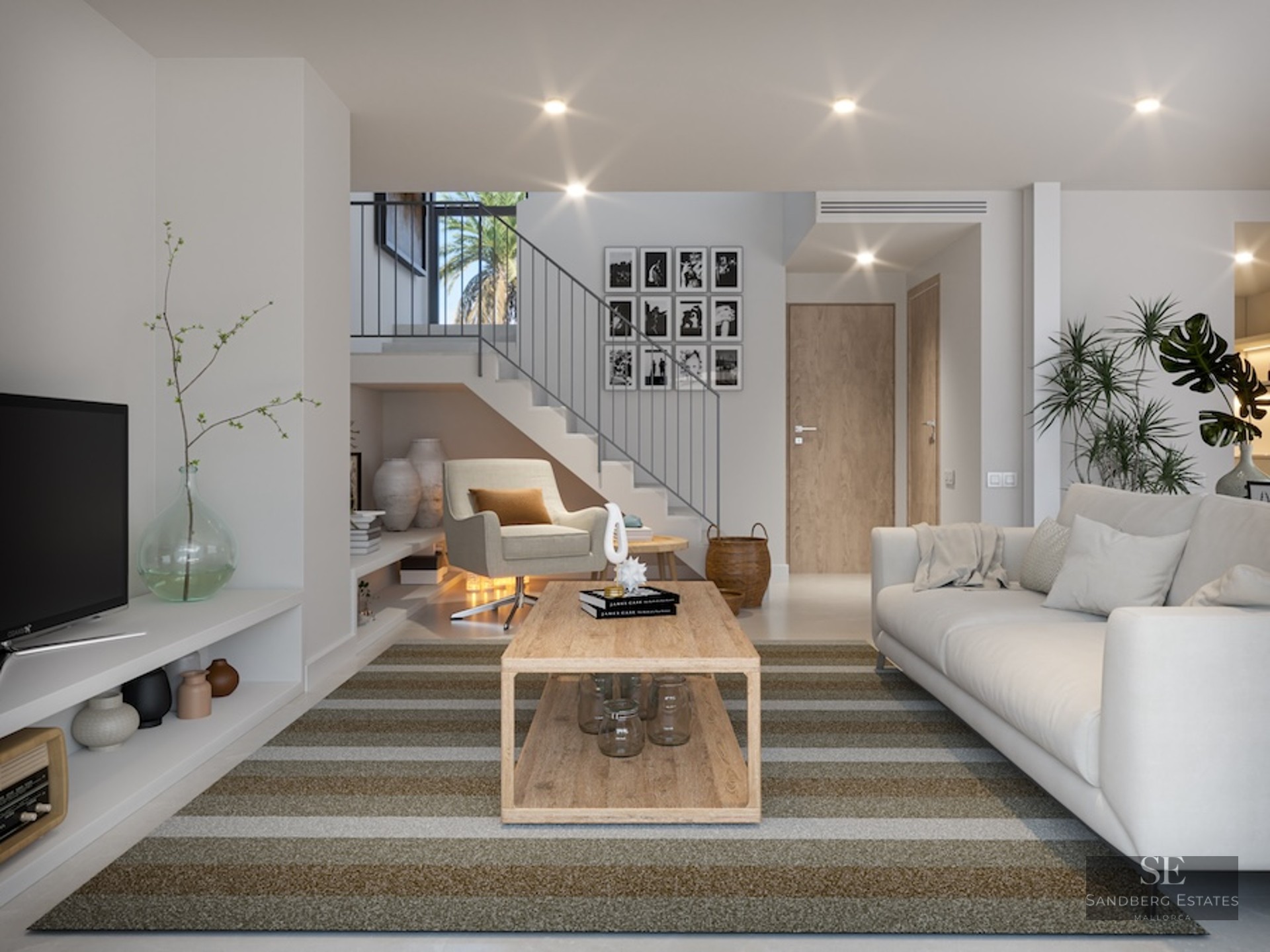 Bright living room featuring a white sofa, wooden coffee table, striped rug, and a modern staircase in the background.