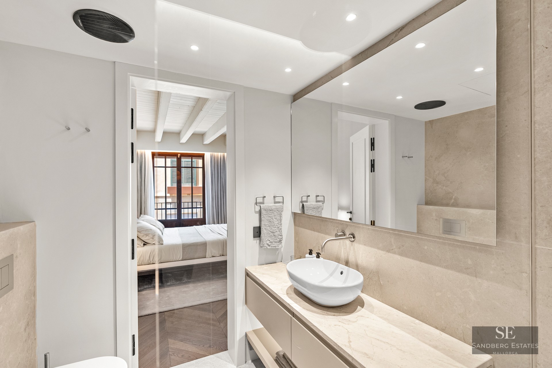 Luxury bathroom featuring a stone countertop, oval vessel sink, and a view into a bright bedroom.