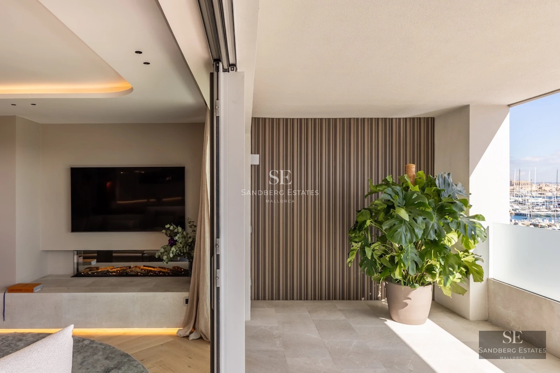 Terrace with sea view. Glass railing, light wood flooring, and modern furniture. Minimalist design with abundant natural light.