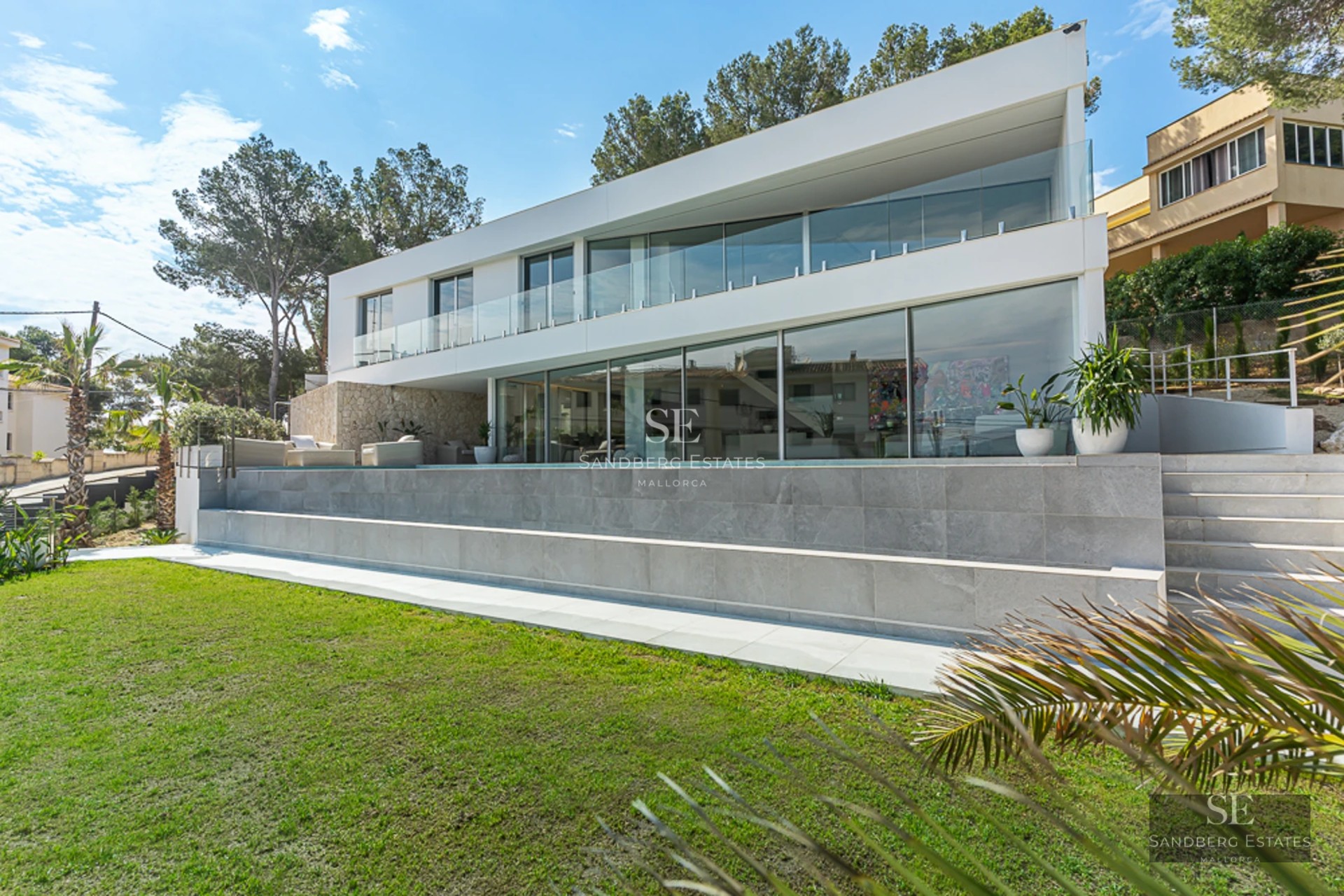 Spacious terrace with a pool surrounded by greenery. Modern design with wooden floors, glass windows, and panoramic views. Elegant outdoor furniture.