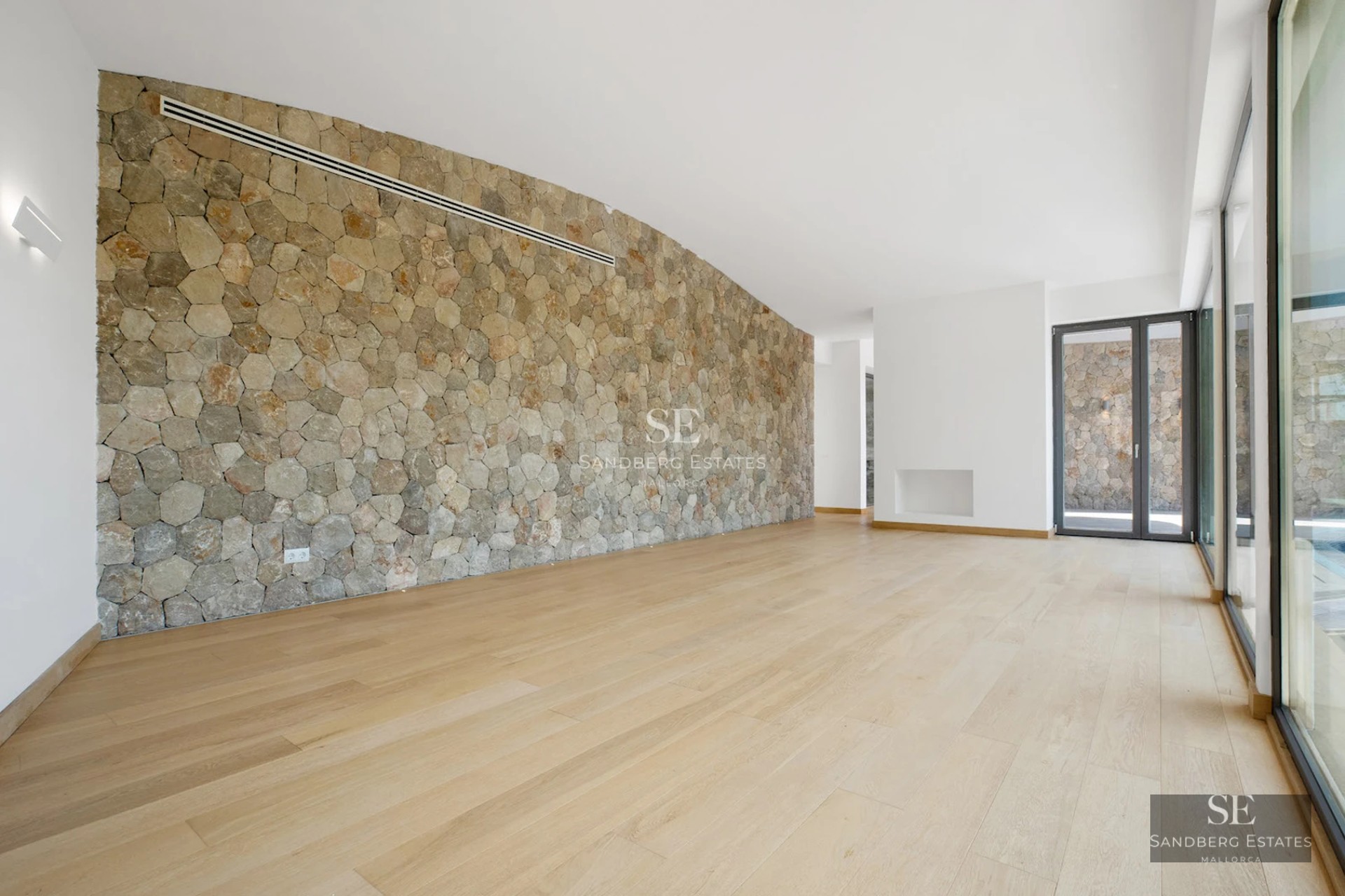 Spacious living room with fireplace, large windows, and access to a terrace with a pool. Modern and elegant design with abundant natural light.