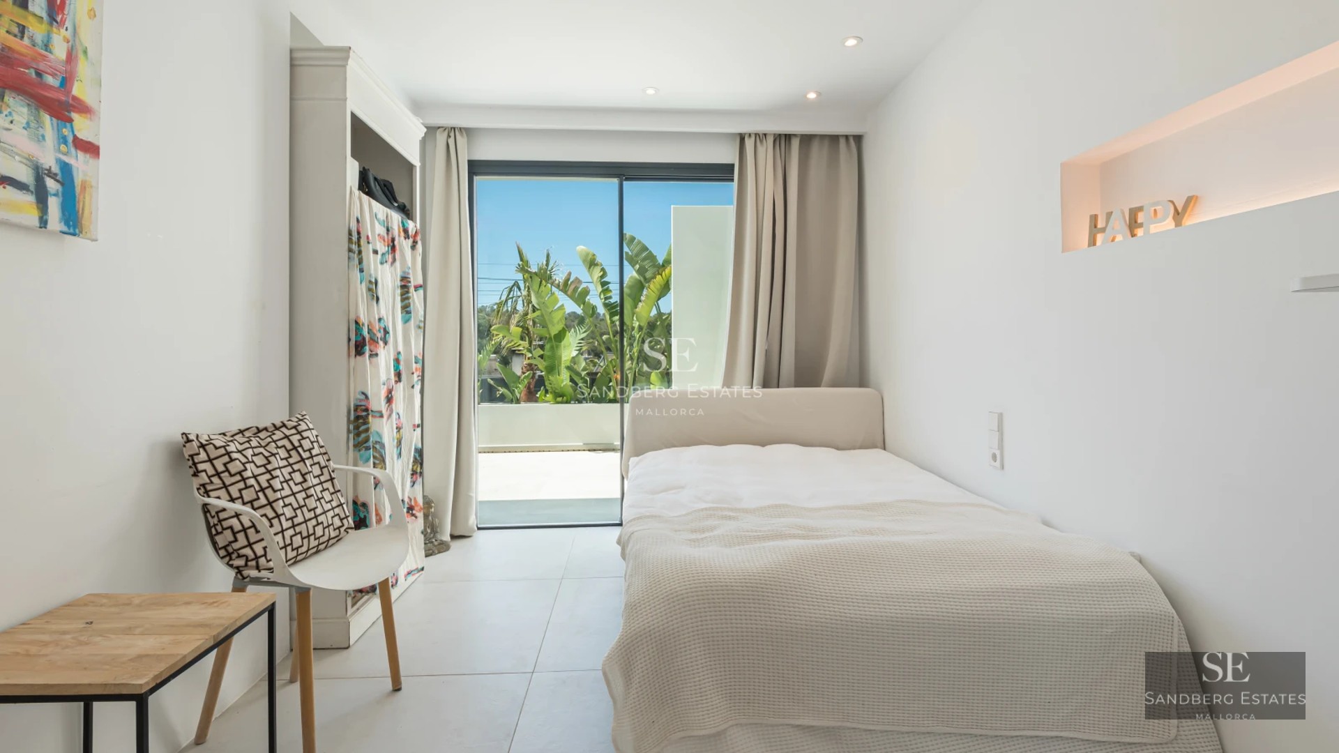 View of infinity pool with armchairs, lush vegetation, and modern architecture with large windows.
