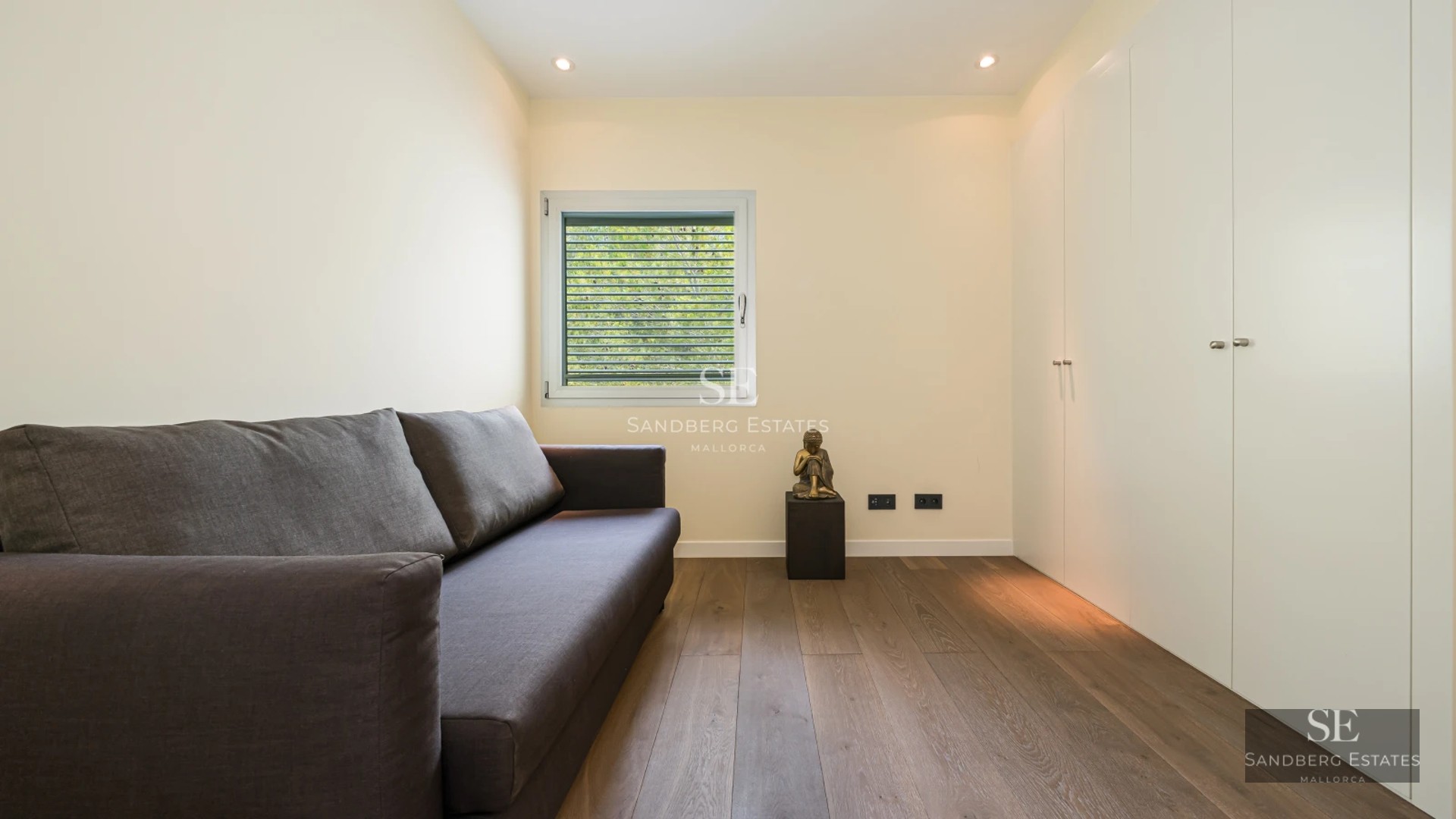 Spacious, bright living room with large windows, light wood floors, and modern furniture. Garden view. Minimalist and elegant design.