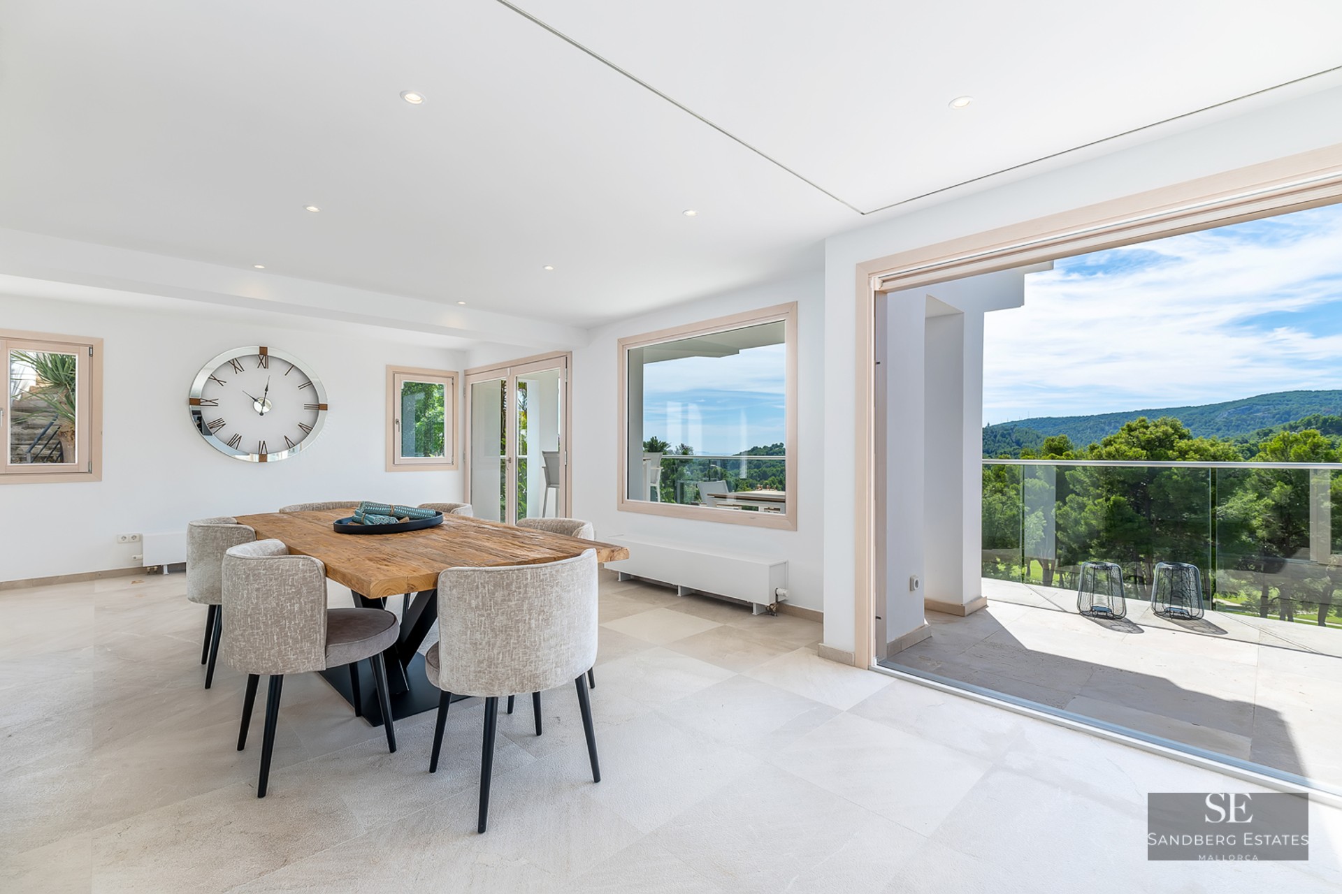 Bright dining room featuring a solid wood table, grey chairs, and terrace access with mountain views.