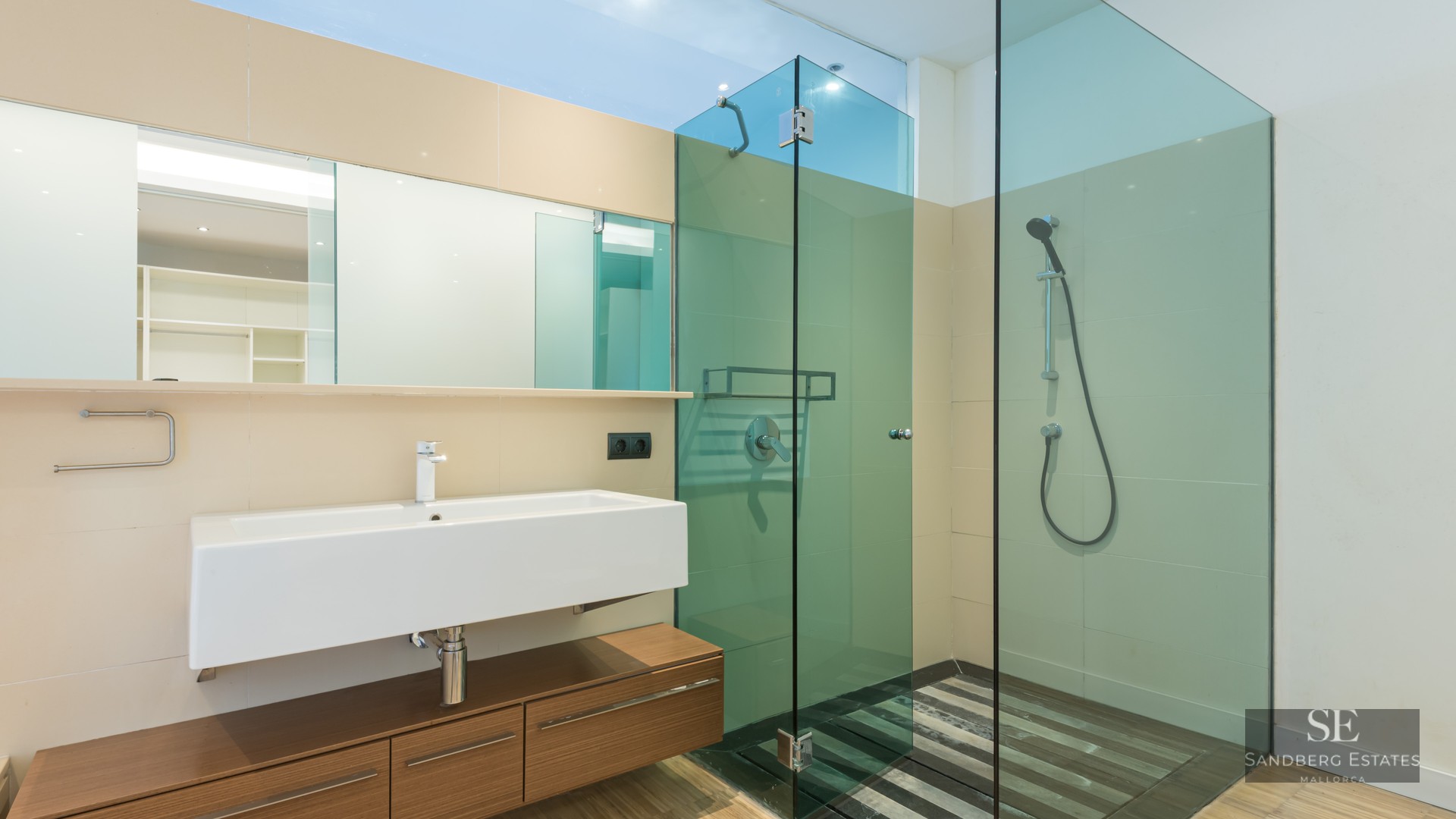 Modern bathroom featuring a white rectangular sink, floating wood vanity, and a green-tinted glass walk-in shower.