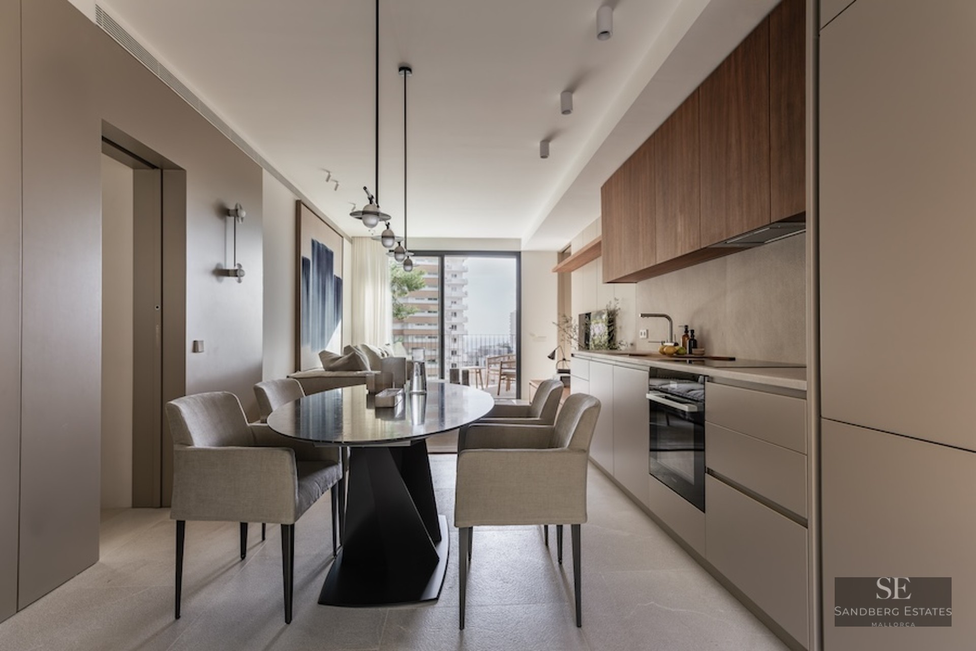 Contemporary dining room with oval black table, grey chairs, and a minimalist integrated kitchen with balcony access.