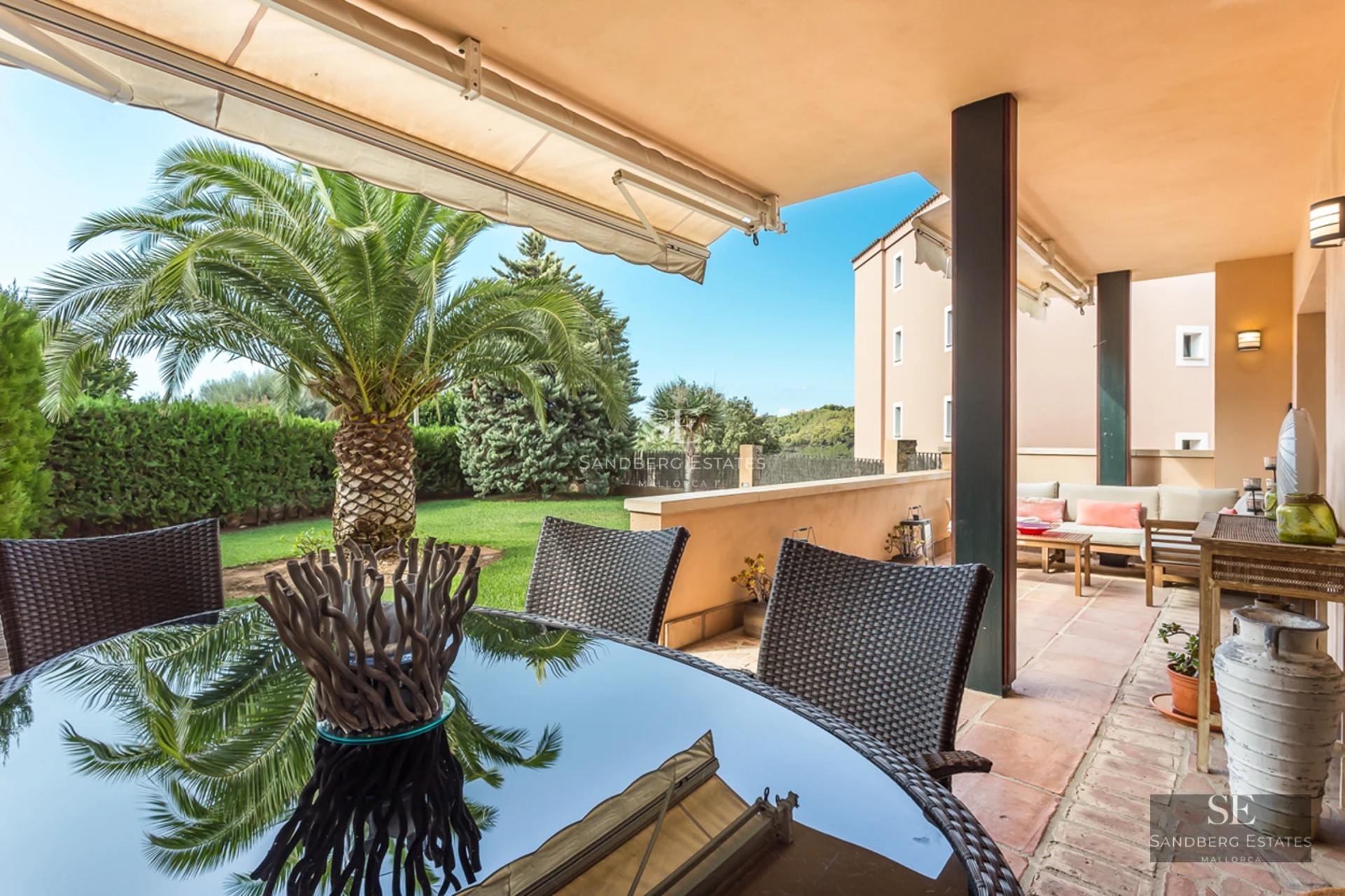 Image of a designer pool with lounge chairs, surrounded by greenery and modern architecture. Reflections in the water and blue sky.