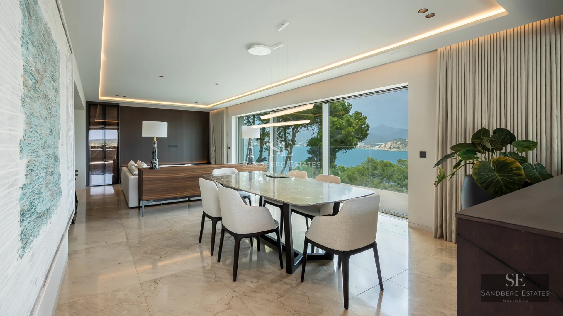 View of infinity pool surrounded by lush greenery. Modern architecture with large windows and natural materials.