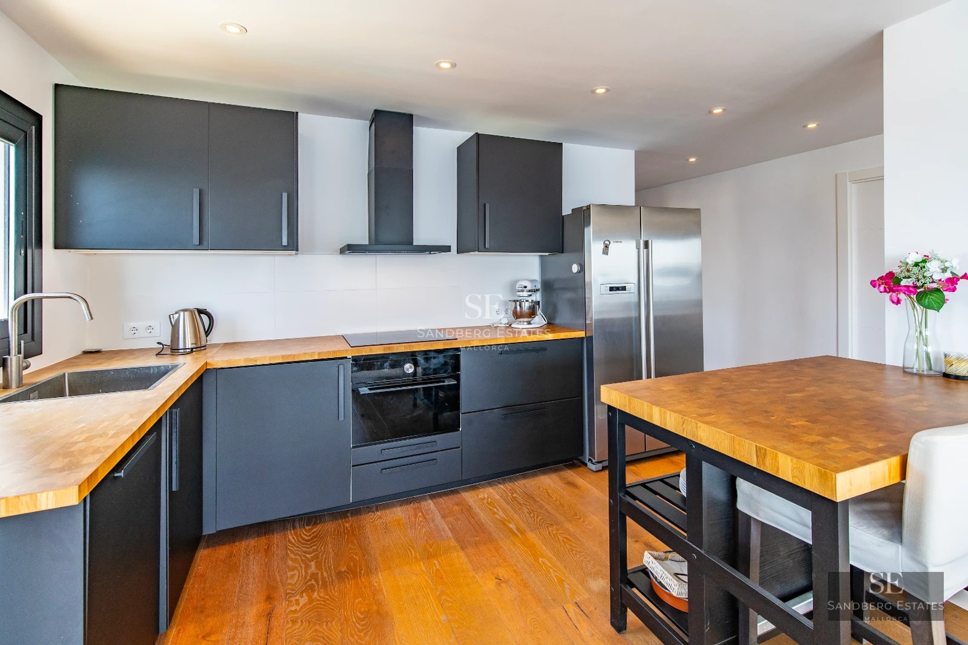 Bright living room with large windows, light wood floor, modern fireplace, and designer furniture. Panoramic outdoor views.